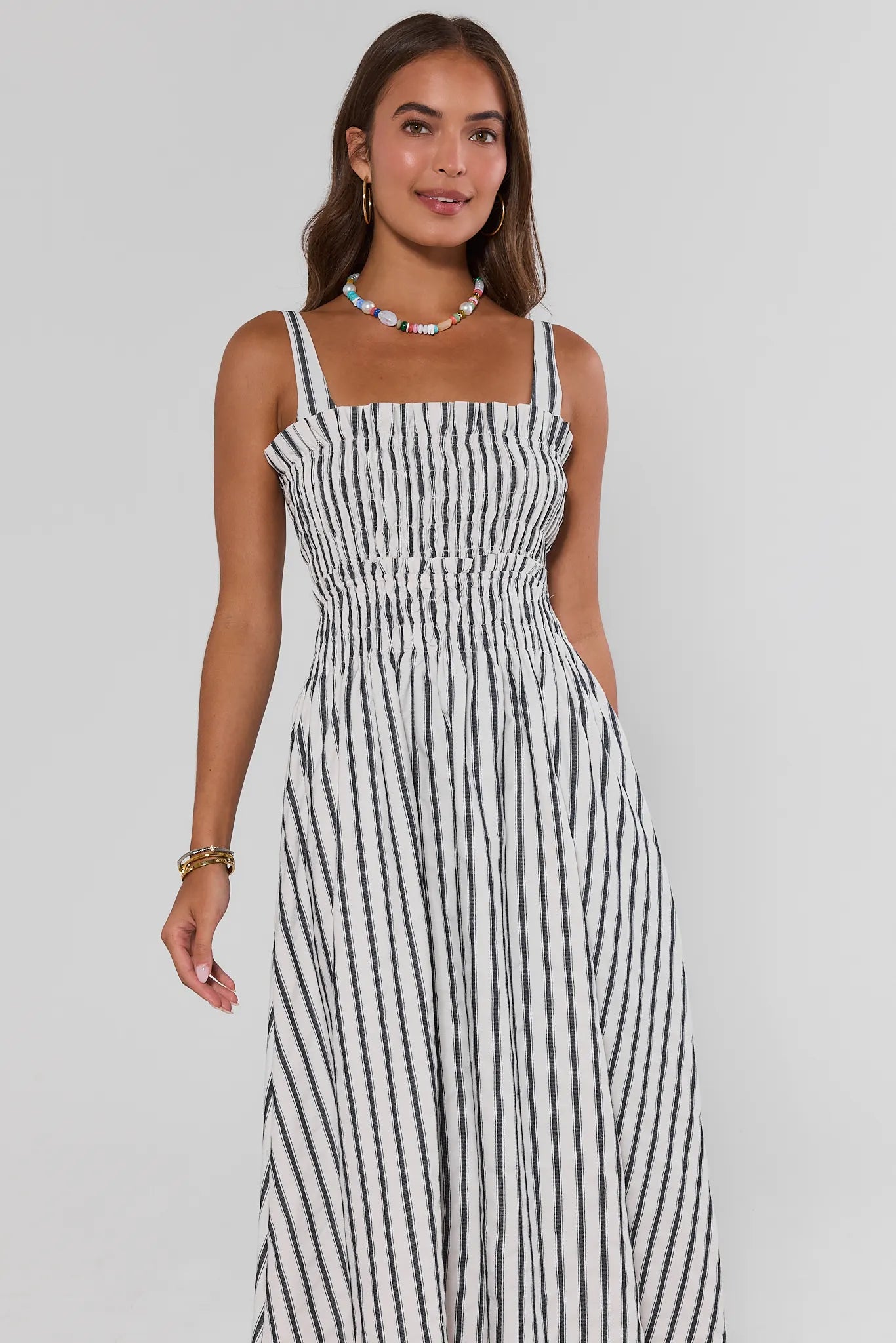 Woman wearing a black and white striped dress on a gray background standing