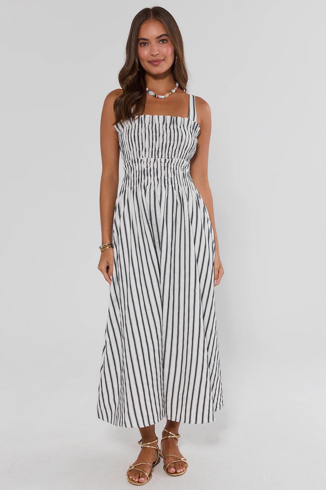 Woman wearing a black and white striped dress on a gray background walking