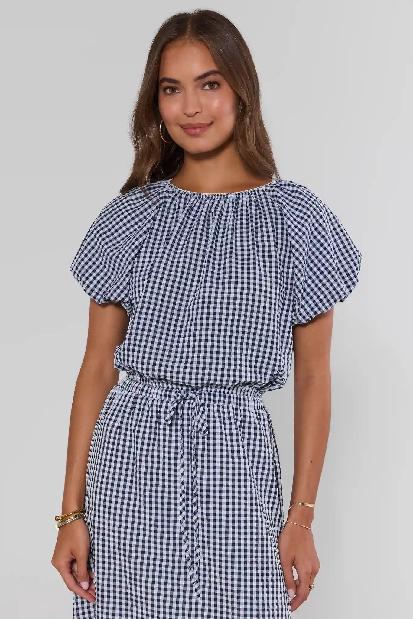 Woman wearing a blue and white checkered dress against a plain background