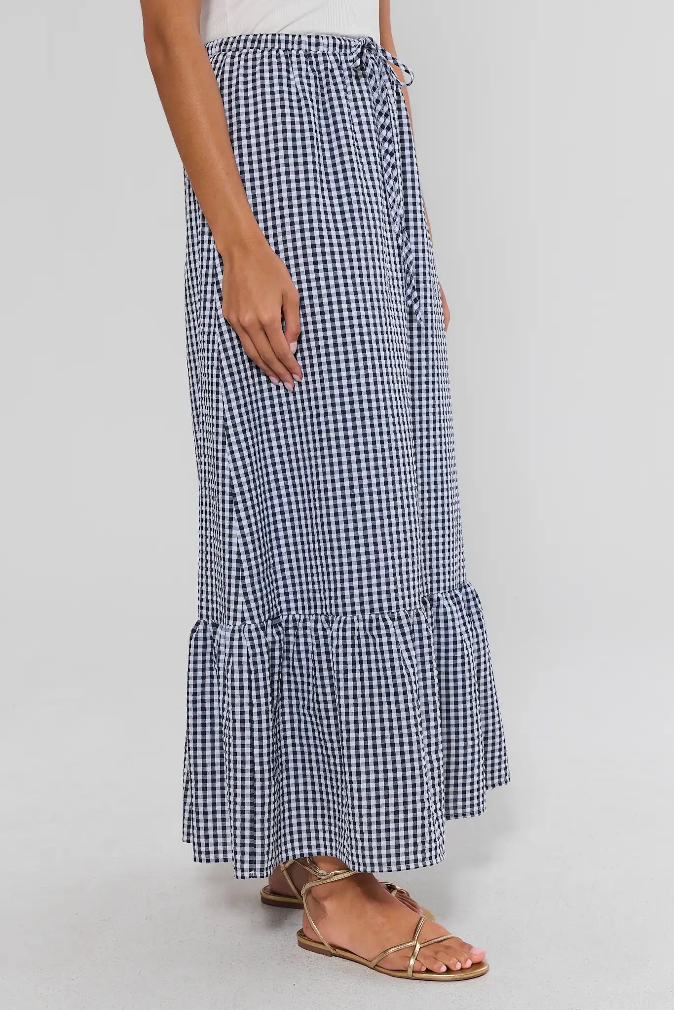 Person wearing a blue and white checkered skirt on a plain background side