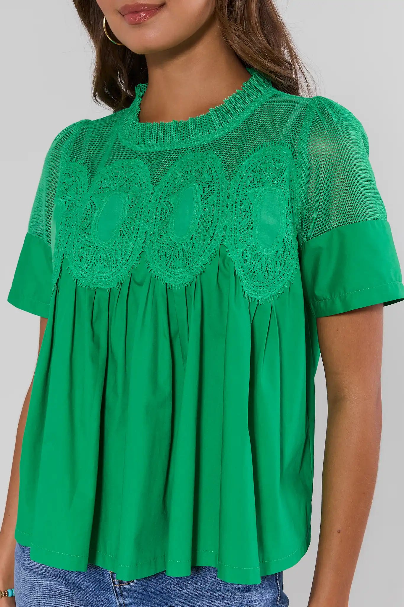Green blouse with lace details on a plain background close up