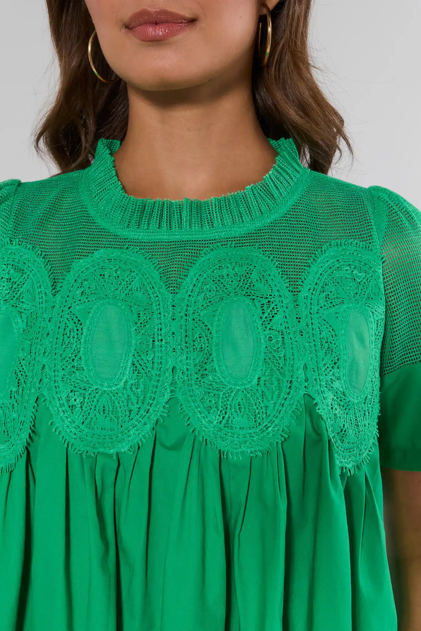 Green dress with lace details on a plain background detailed