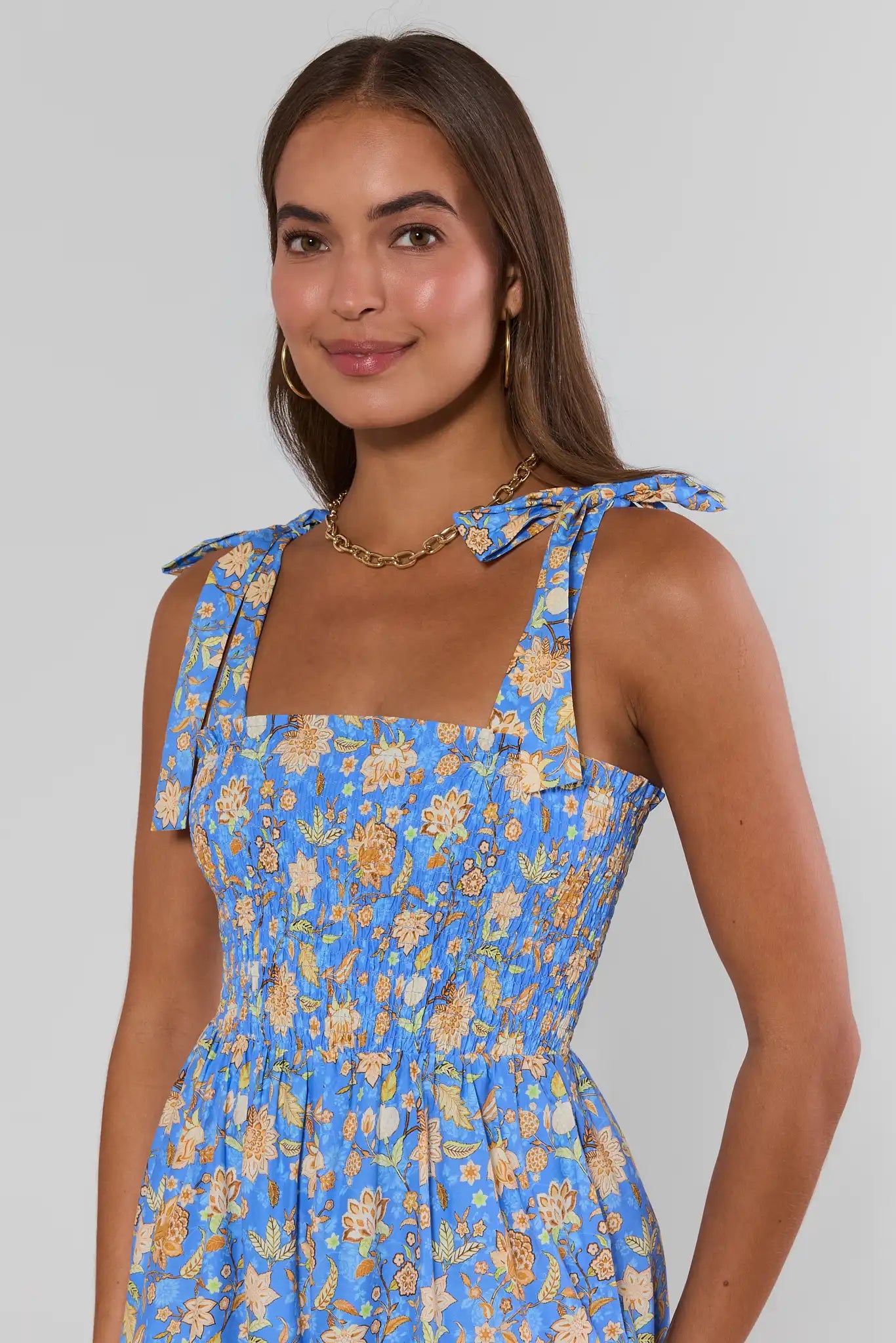 Woman wearing a blue floral dress against a plain background close up