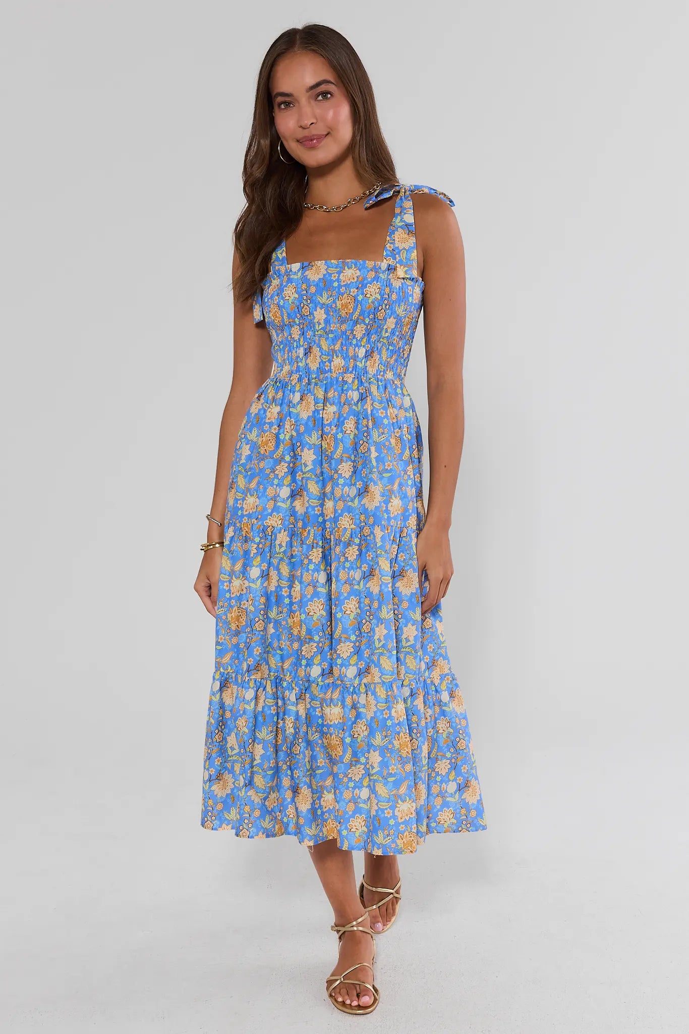 Woman wearing a blue floral dress on a gray background walking