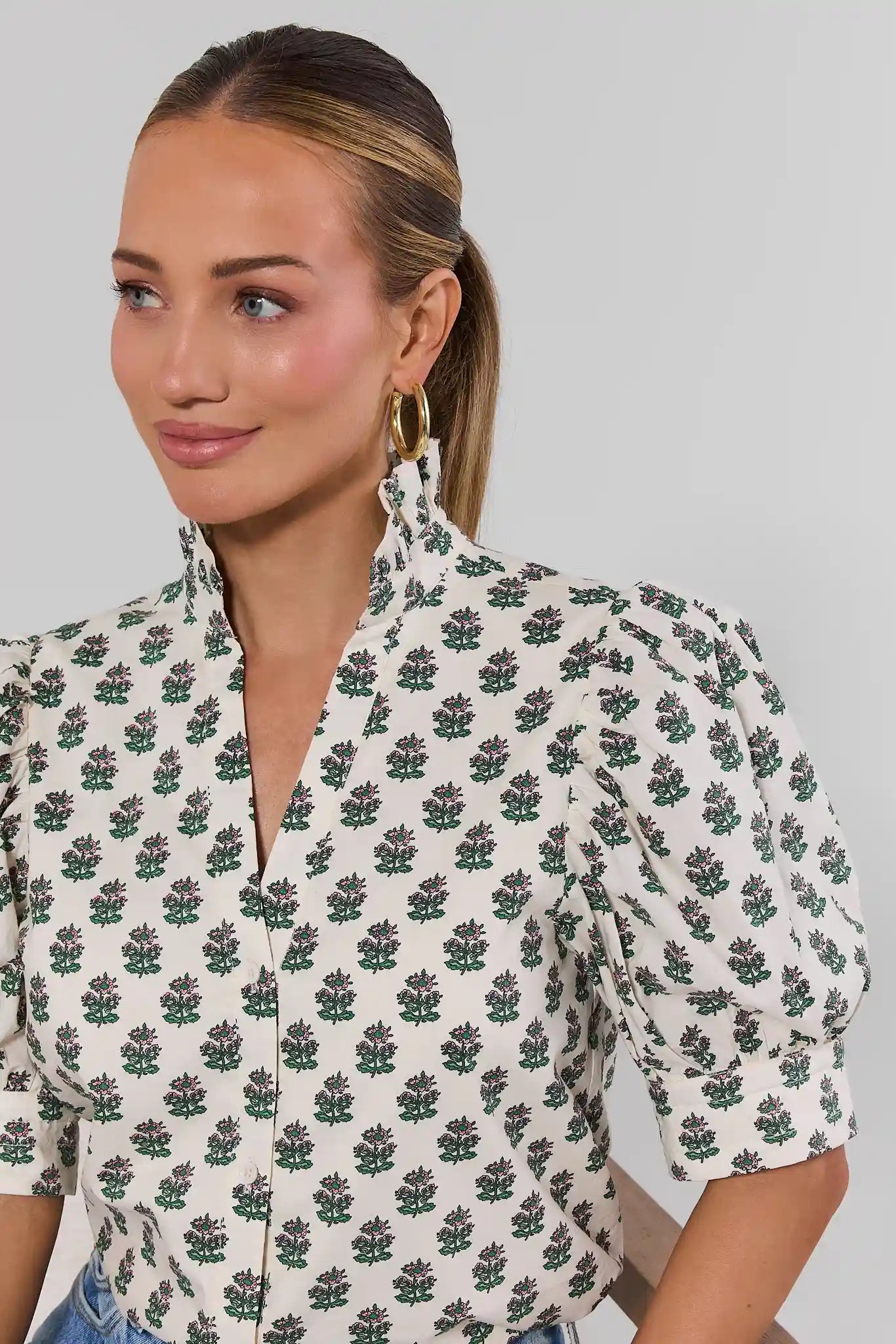 Woman wearing a floral patterned blouse against a plain background close up
