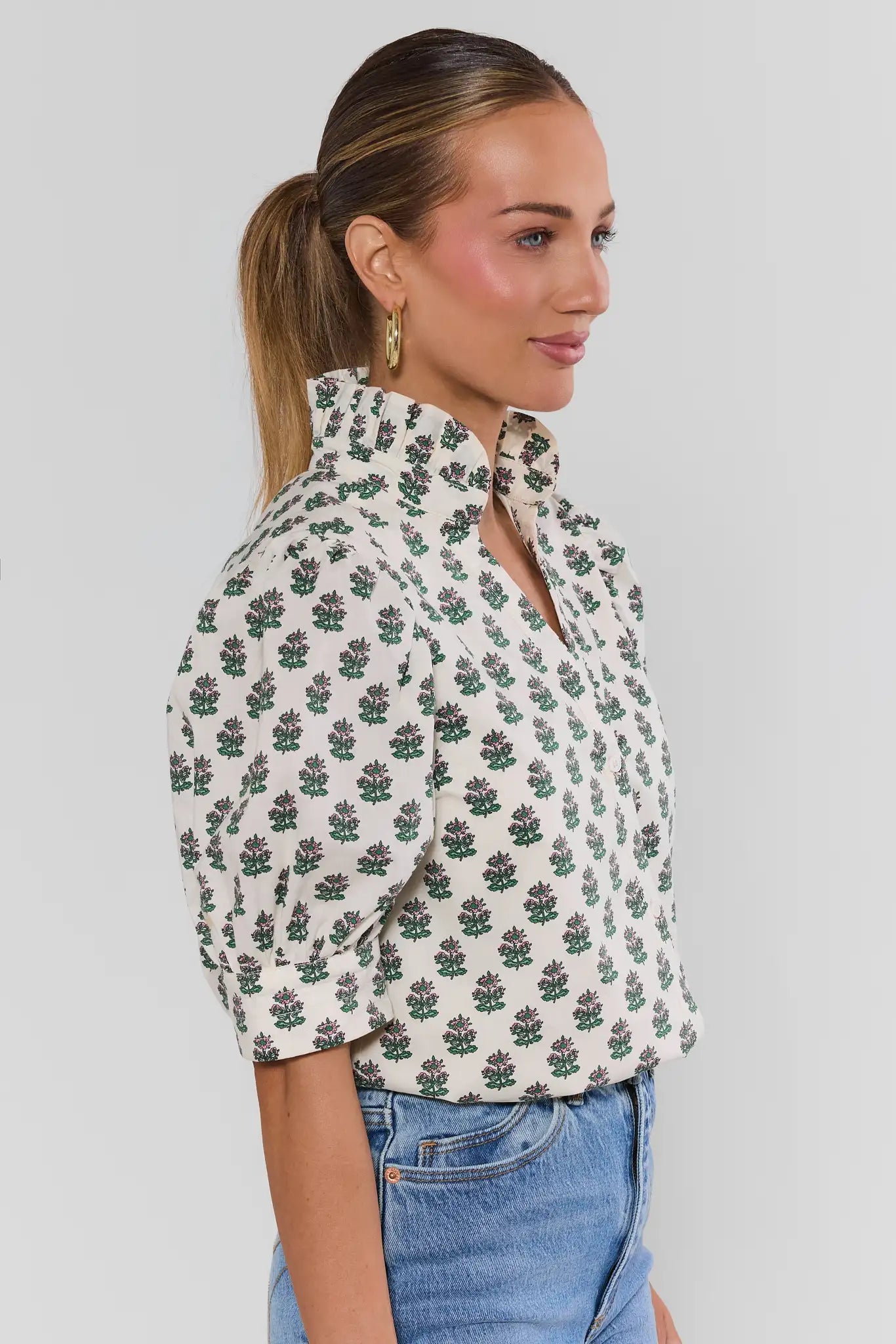 Woman wearing a floral blouse with a plain background side
