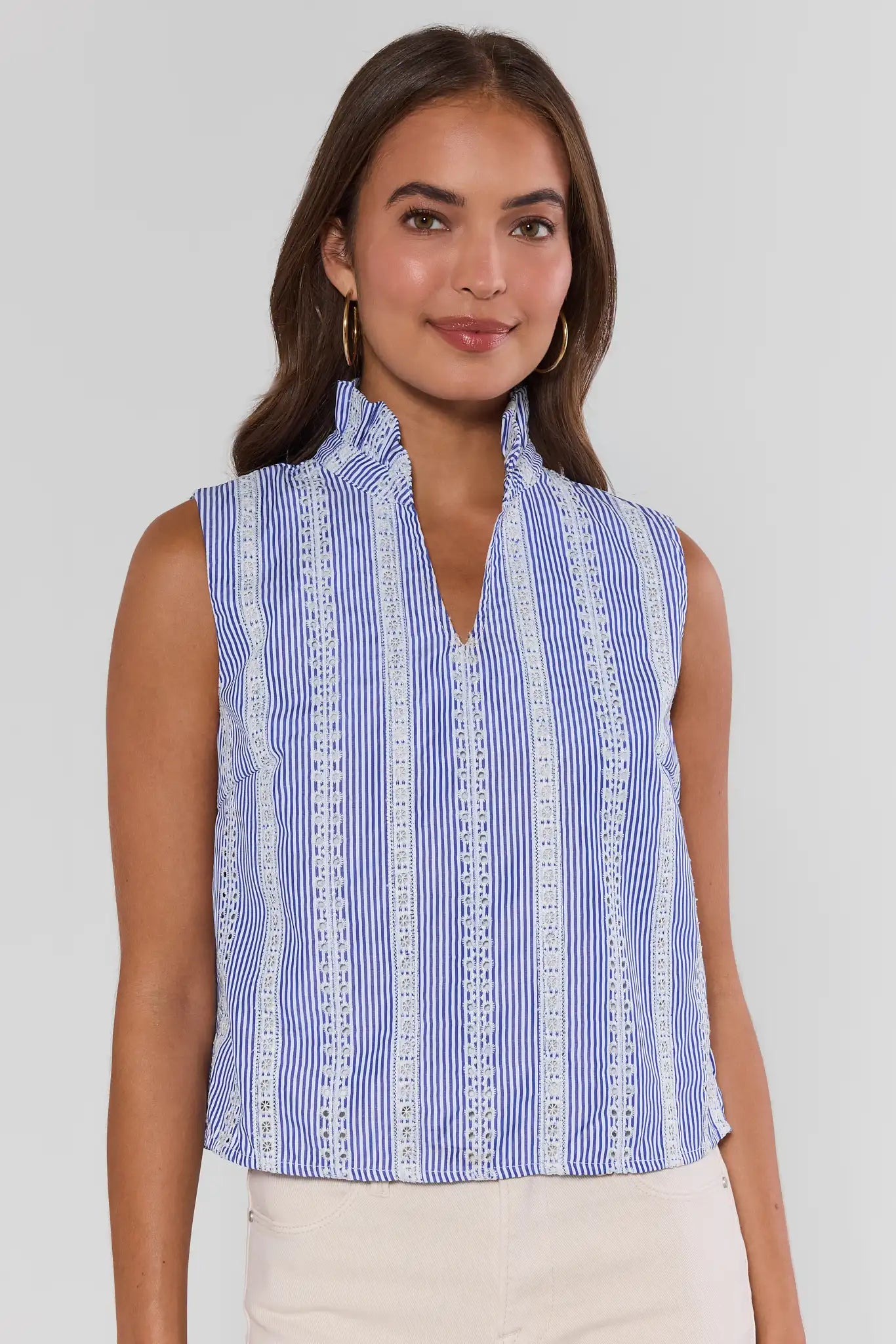 Woman wearing a blue and white striped sleeveless top against a plain background