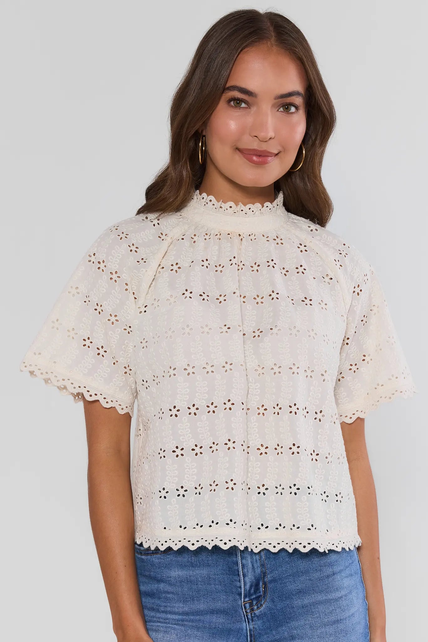 woman wearing white floral eyelet top on white background
