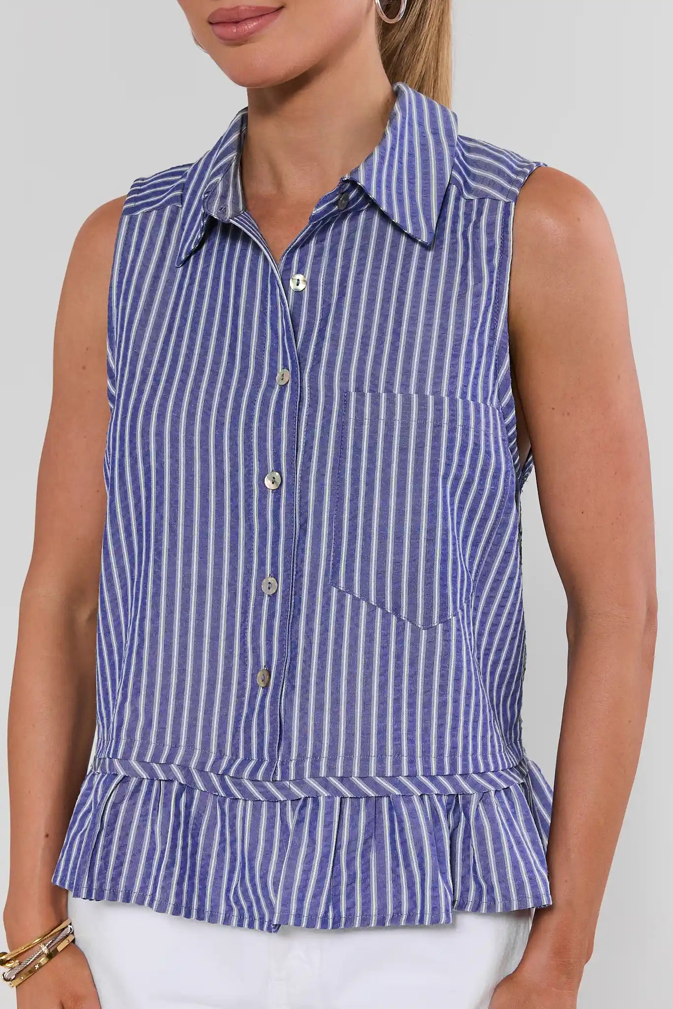 Woman wearing a blue and white striped sleeveless shirt against a plain background close up