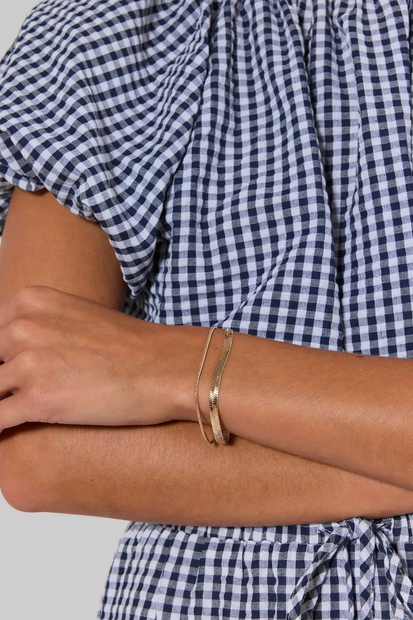 woman wearing Gold bracelet on a light gray background