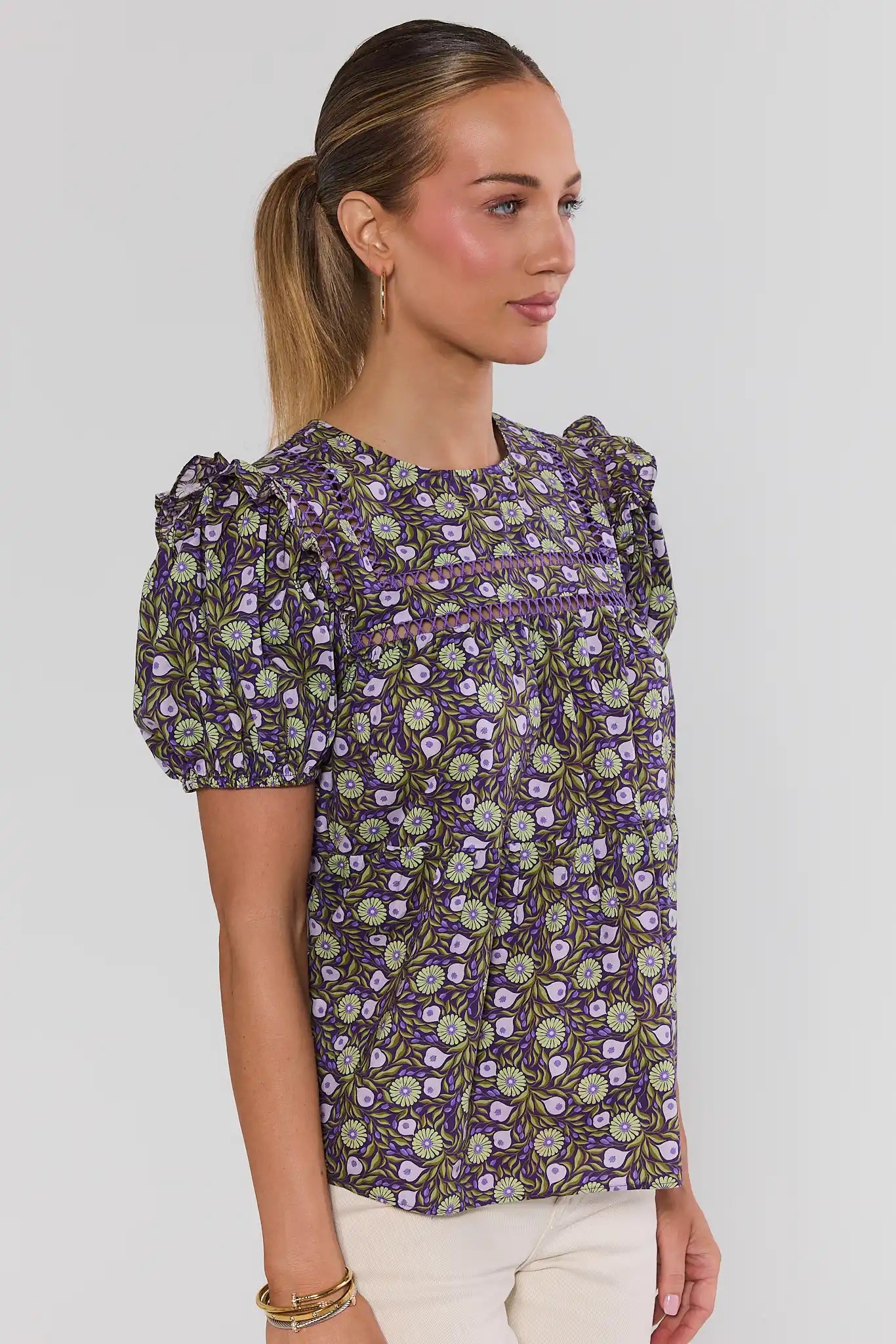 Woman wearing a purple floral blouse against a plain background side
