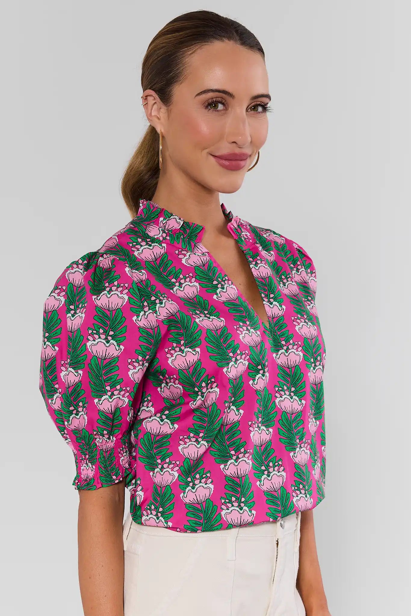 woman wearing amanda pink floral green top on white background turned to side