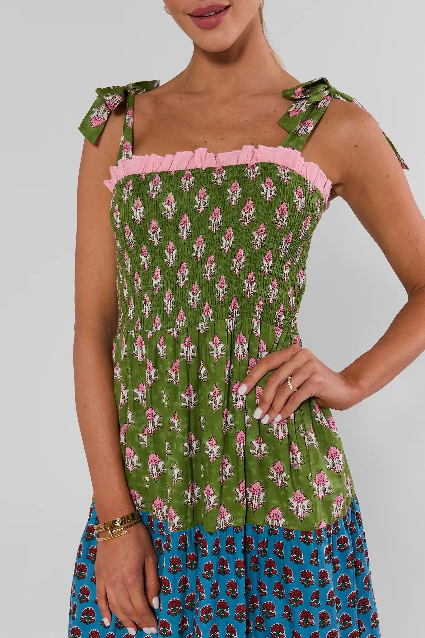 Close up of A woman modeling a sleeveless tiered maxi dress with a colorful patchwork print, 