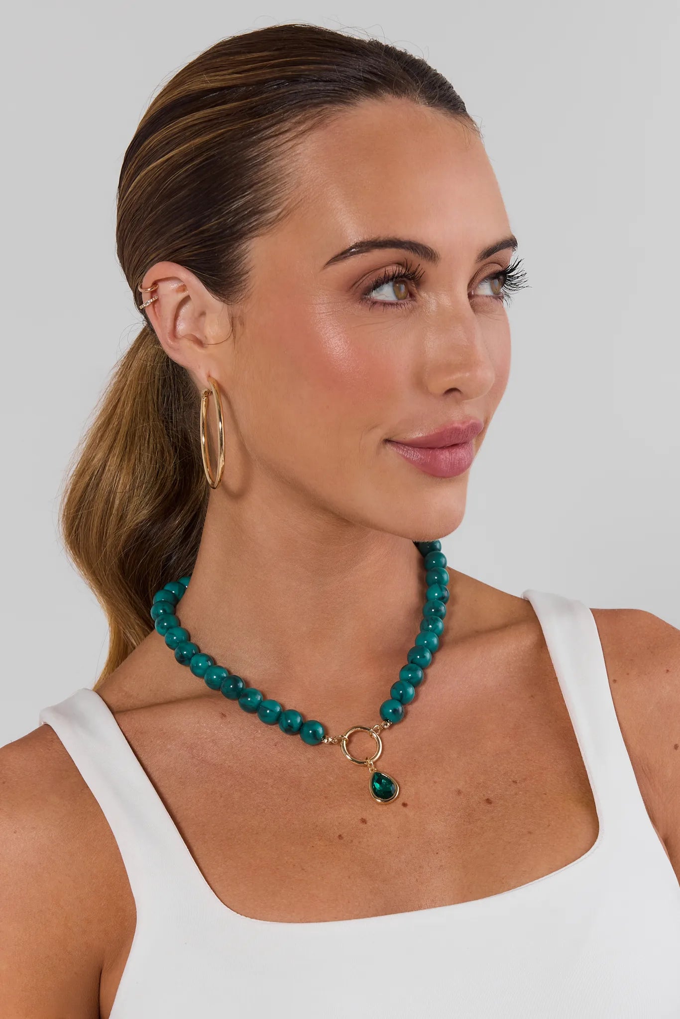 Woman wearing green beaded necklace on white background