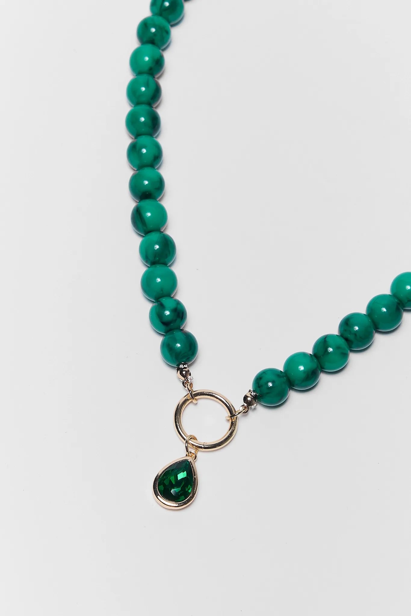 close up of green beaded necklace on white background
