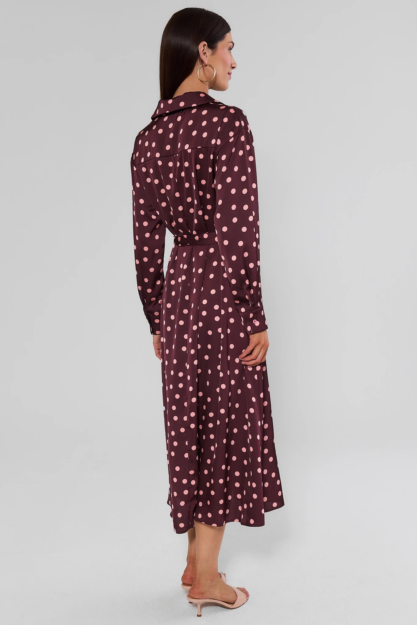 woman wearing brown polka dot dress on white background standing
