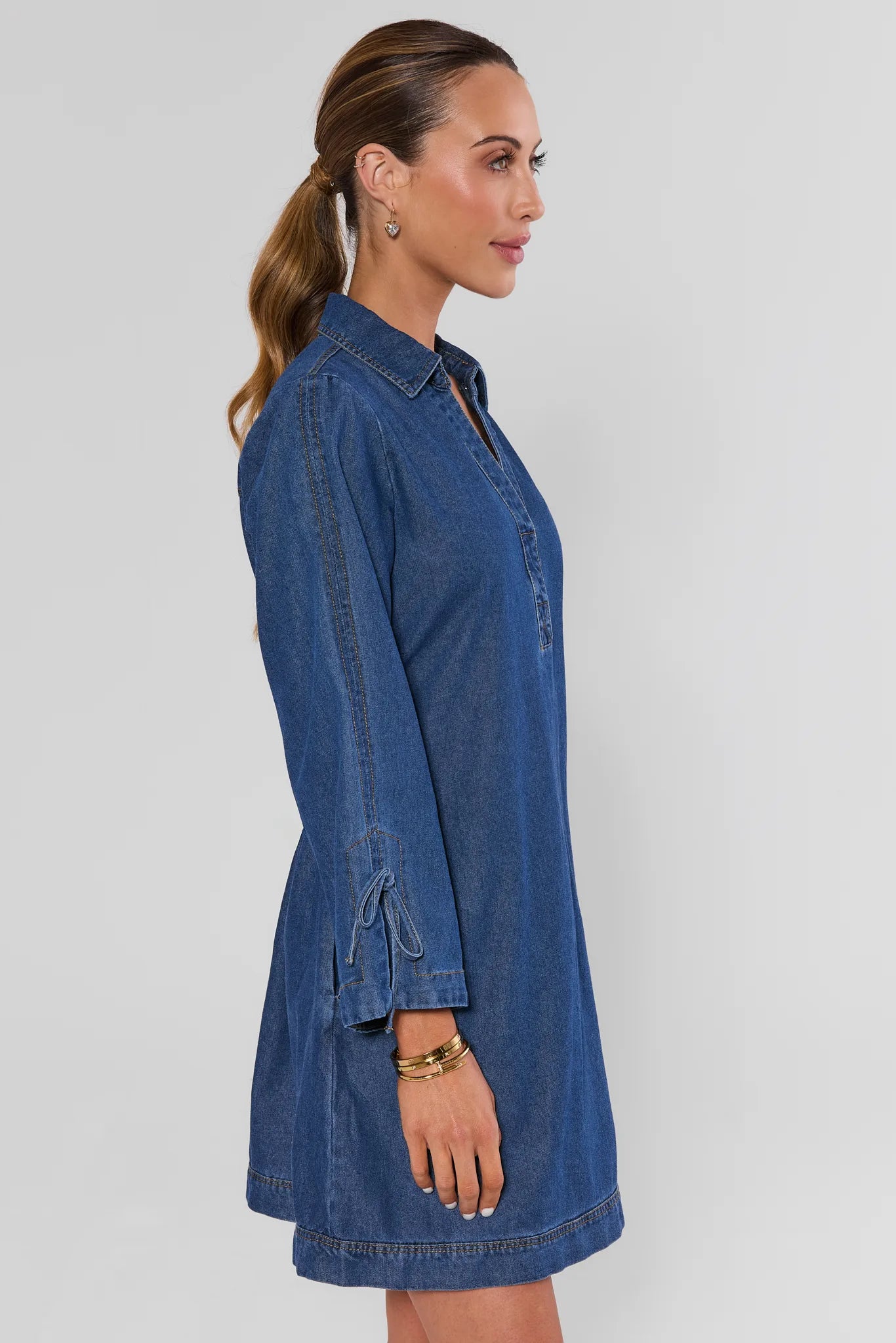 woman wearing shay denim mini dress on a white background standing side