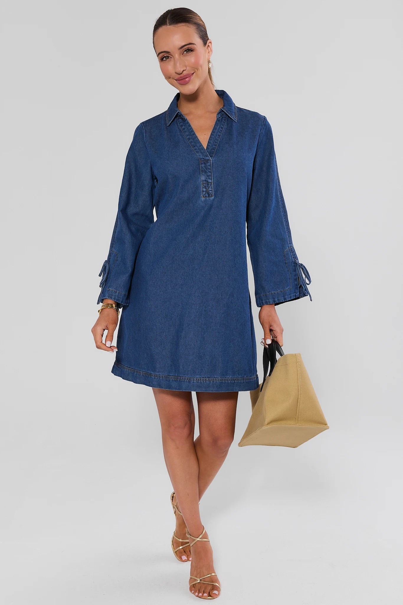 woman walking wearing shay denim mini dress on a white background