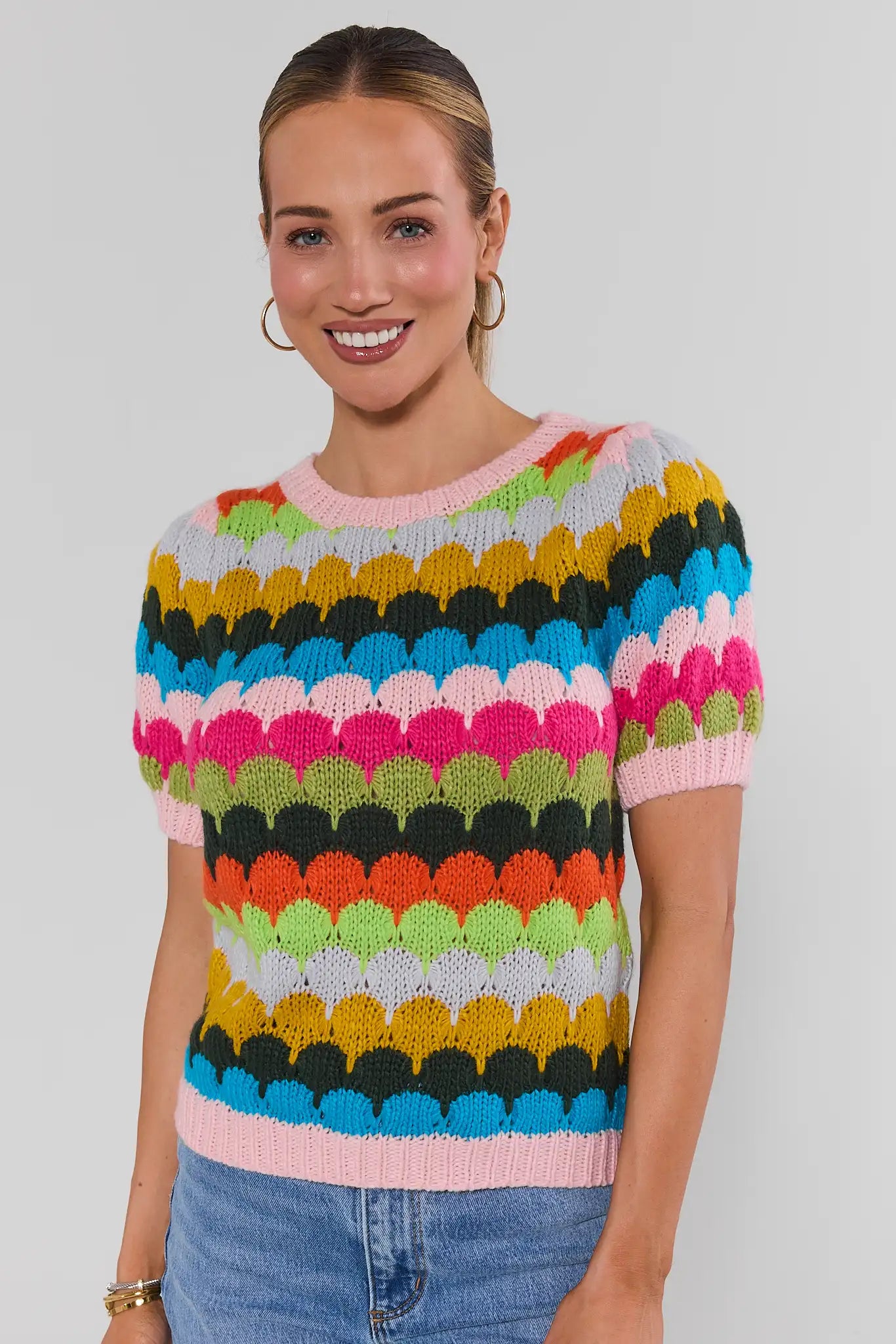 woman wearing trina multi striped knit top with jeans on a white background