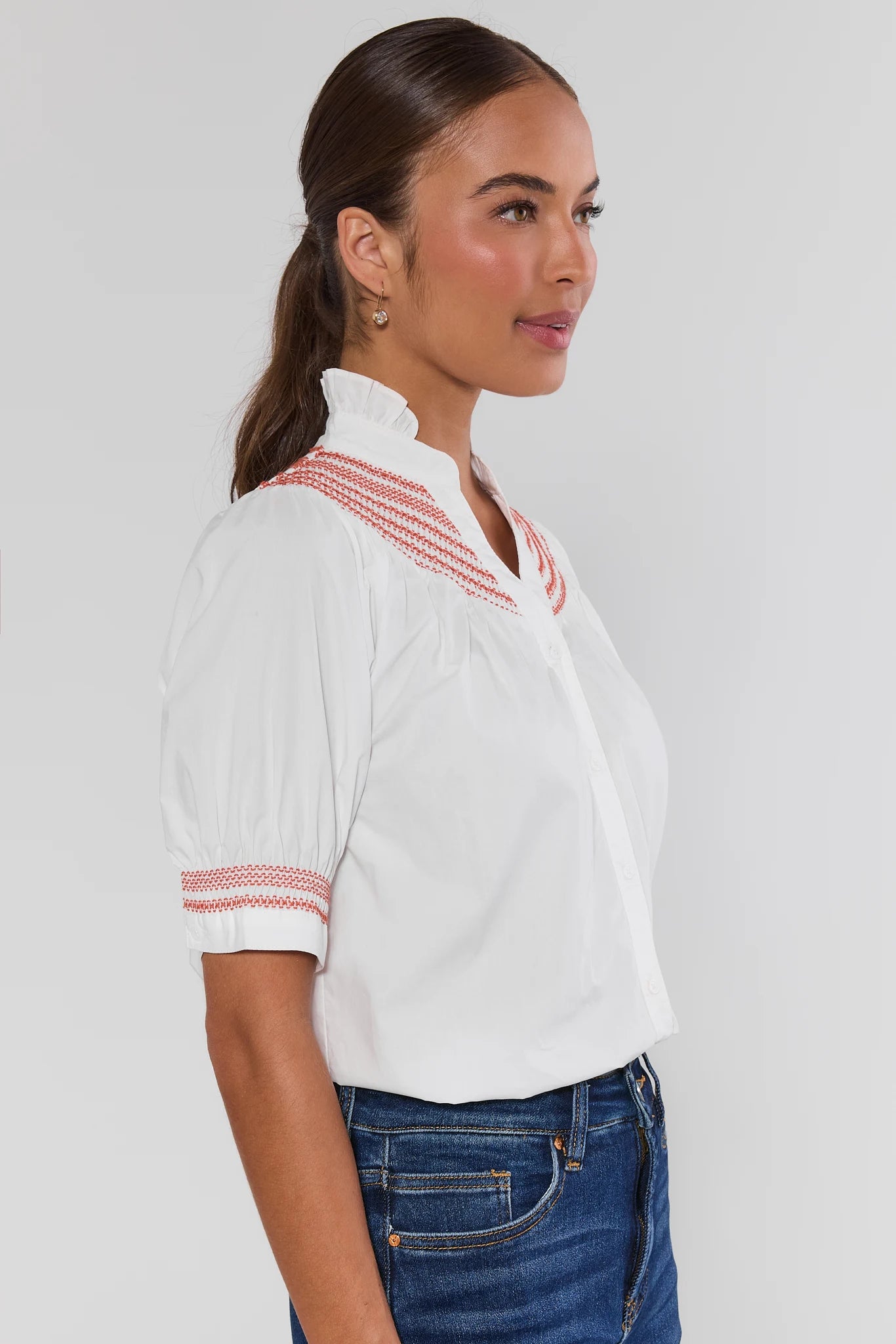 Woman wearing Yvonne White and Orange Embroidered Top on a white background side