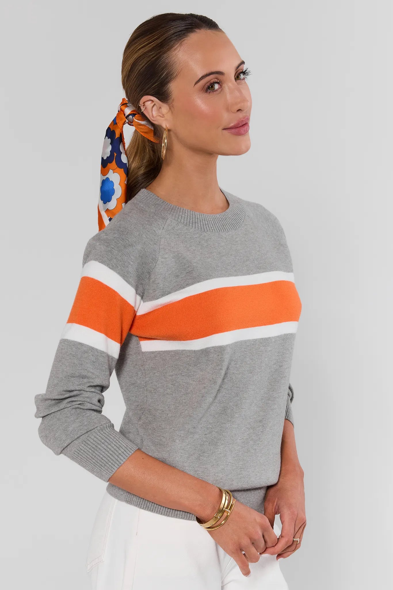 Woman wearing Dylan Orange Stripe Sweater on a white background side 