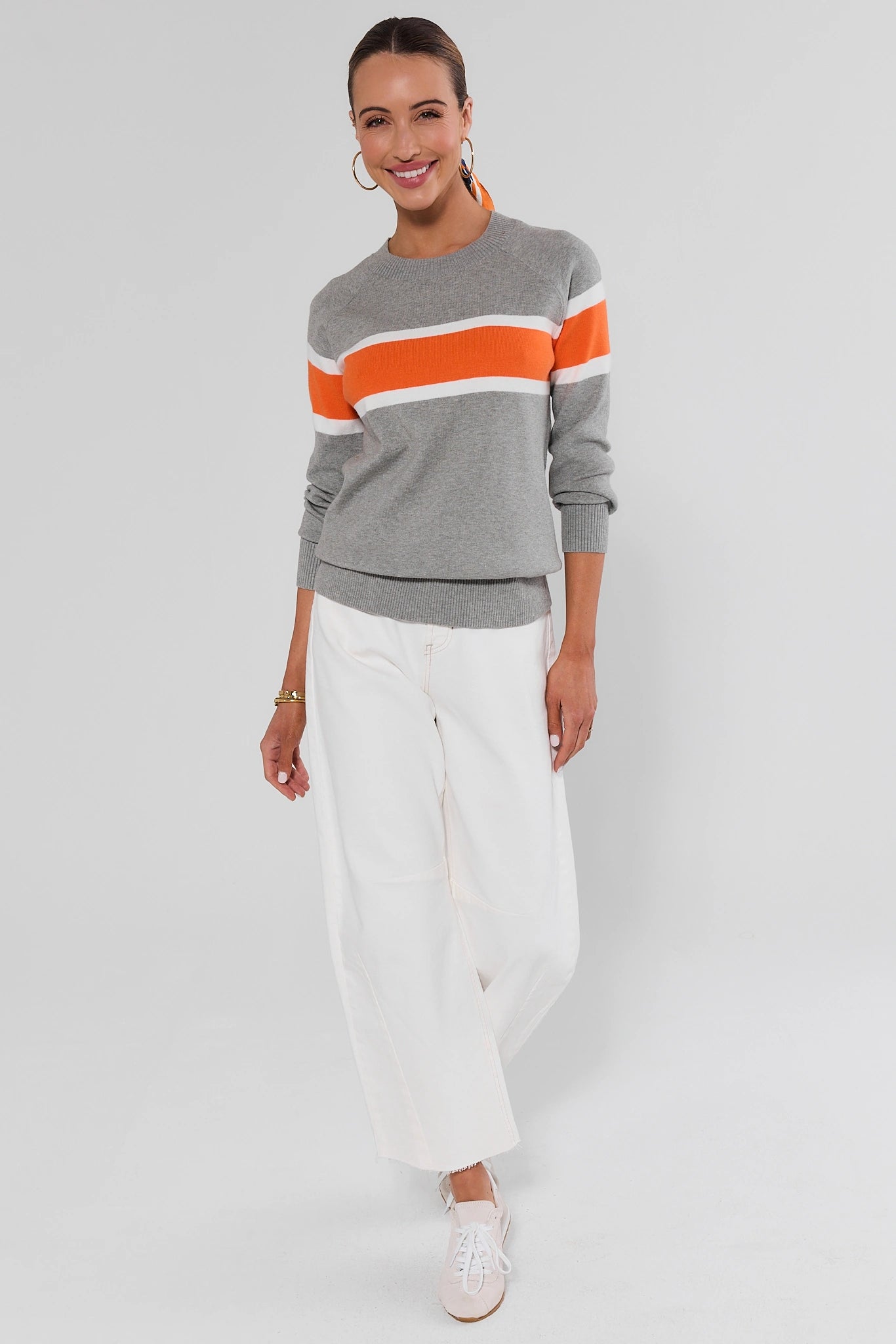Woman walking wearing Dylan Orange Stripe Sweater on a white background