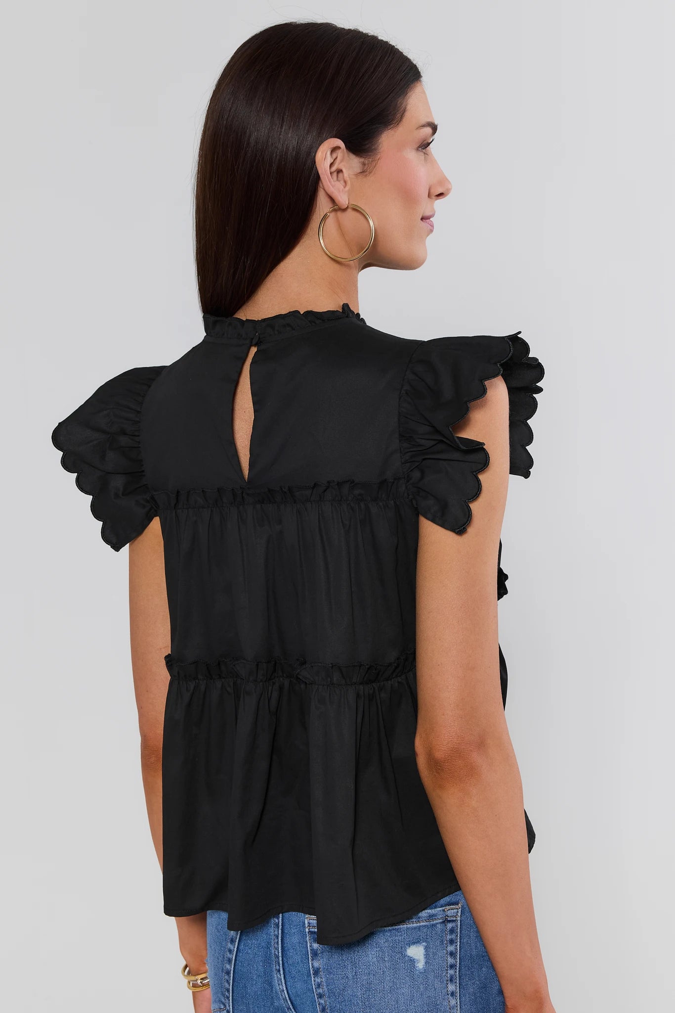 woman wearing Black Tiered Flutter Sleeve Top on a white background turned