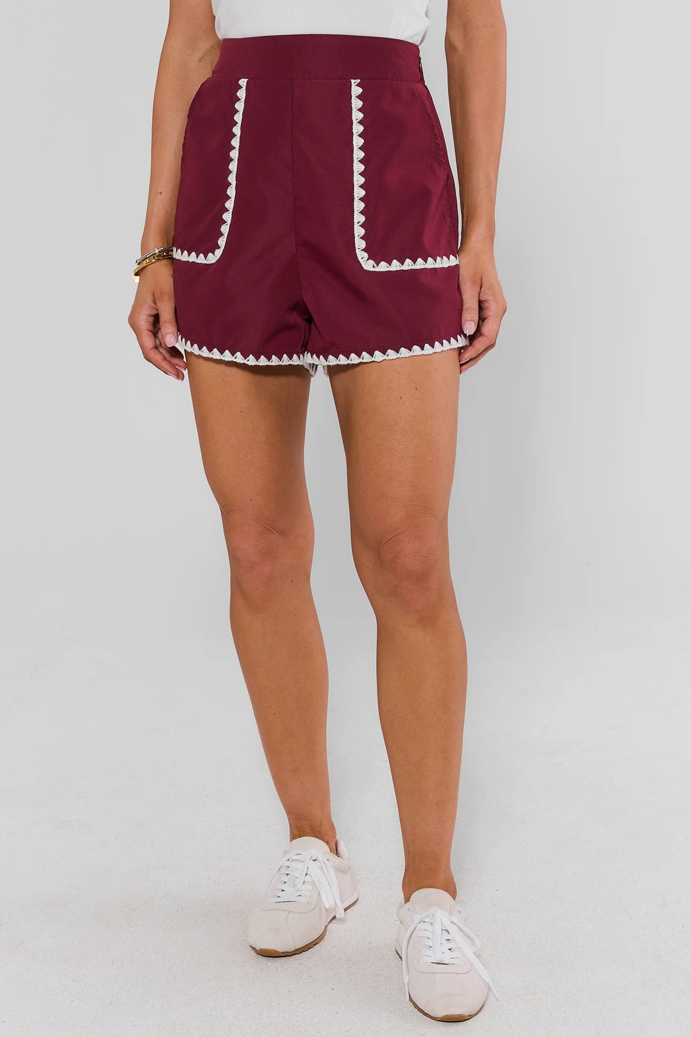 Woman standing wearing Maroon Embroidered Trim Shorts on a white background