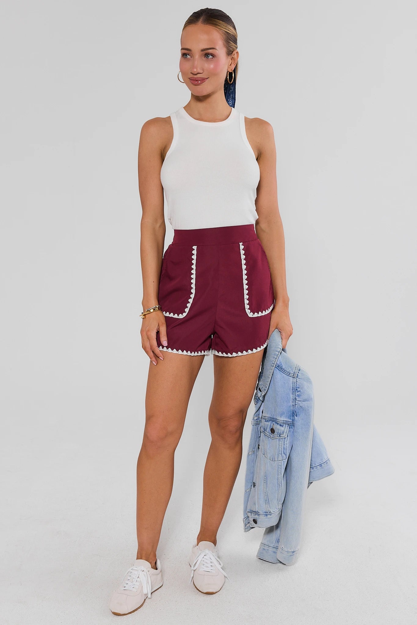 Woman wearing Maroon Embroidered Trim Shorts and a white bodysuit on a white background