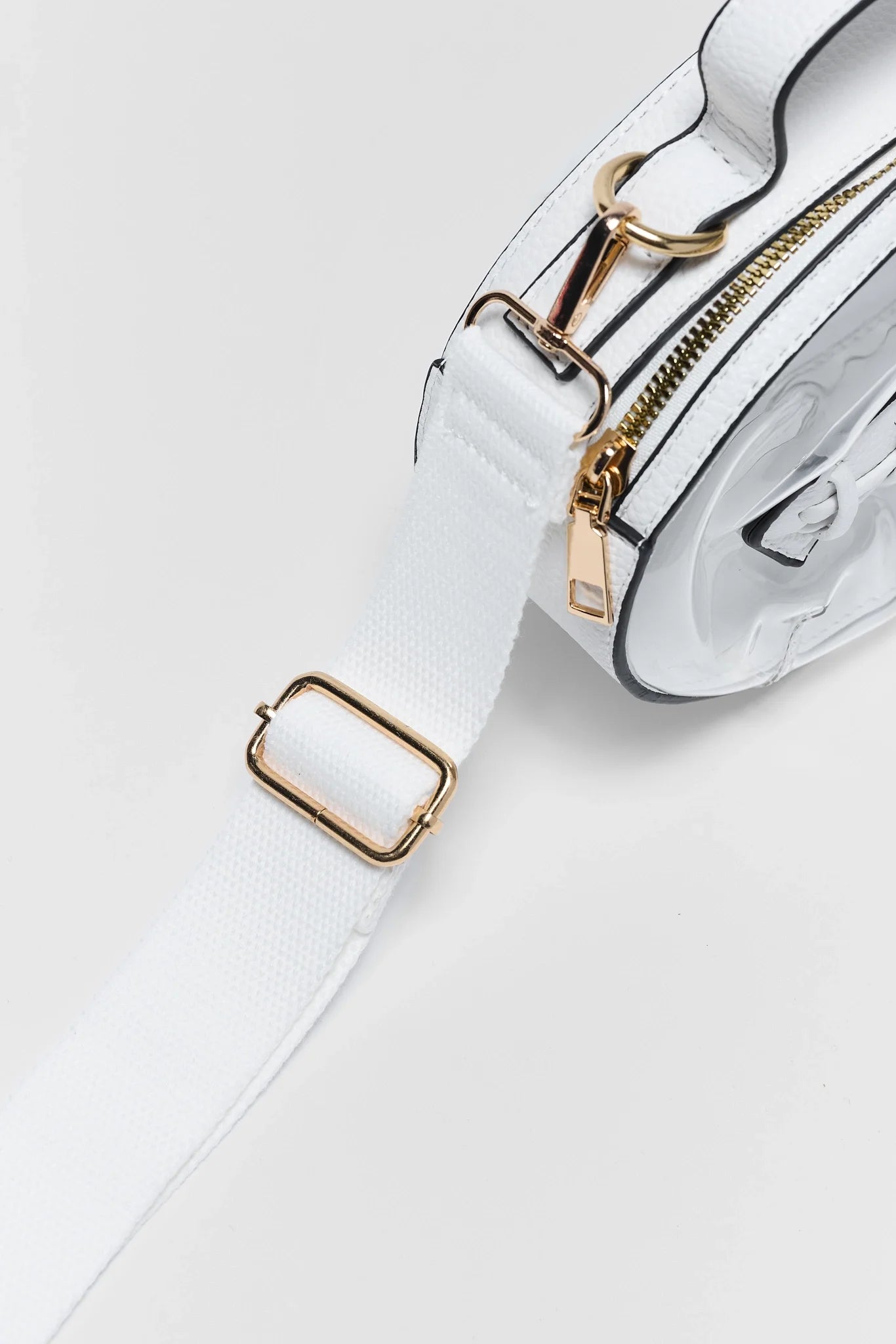 White leather crossbody bag with gold-tone hardware and a matching white strap, shown in a close-up studio shot on a light background.