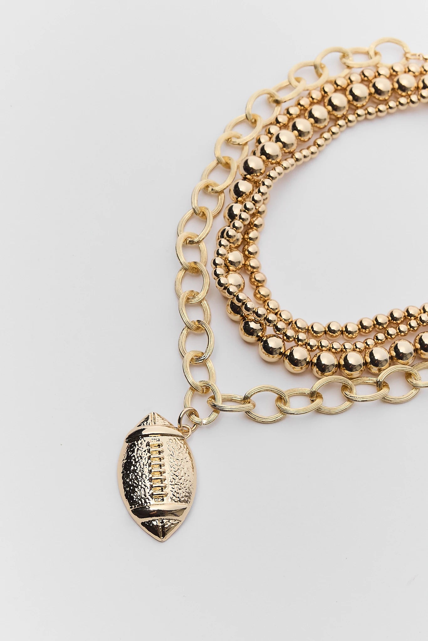 A gold-toned multi-strand chain necklace featuring a football-shaped charm, displayed on a clean white background.