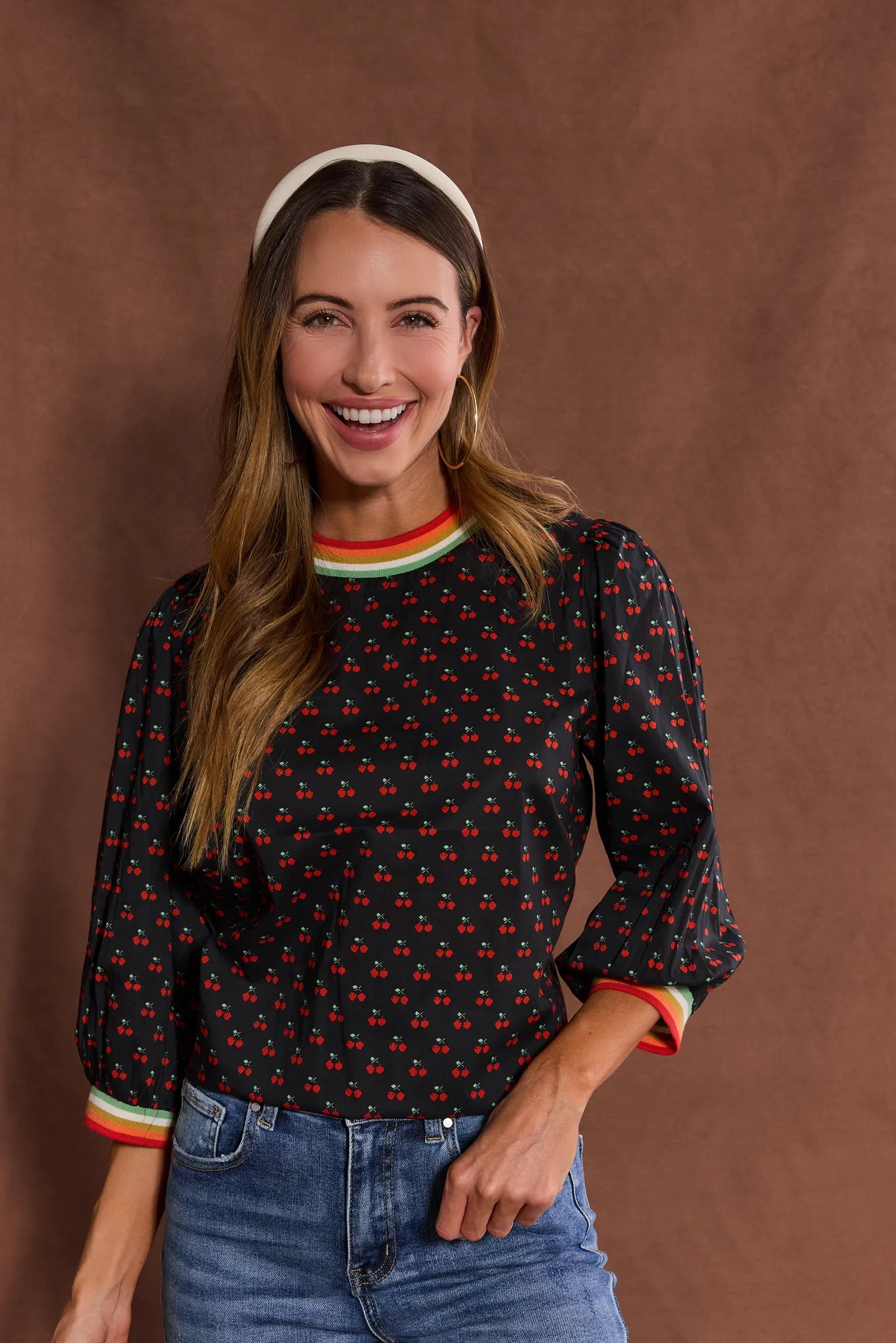 Woman wearing a patterned Bailey Top
 with colorful cuffs and trim against a brown background