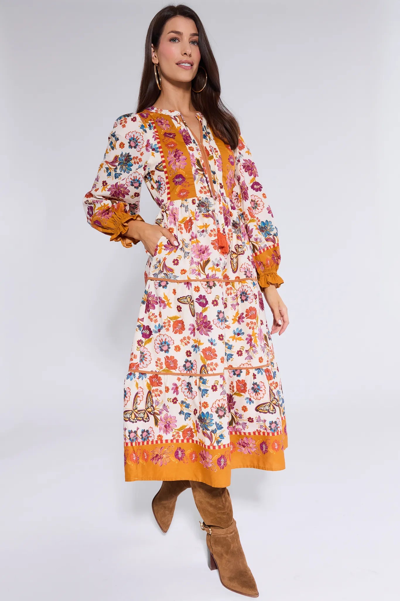 Woman wearing a colorful floral Shiloh Dress with orange accents on a white background