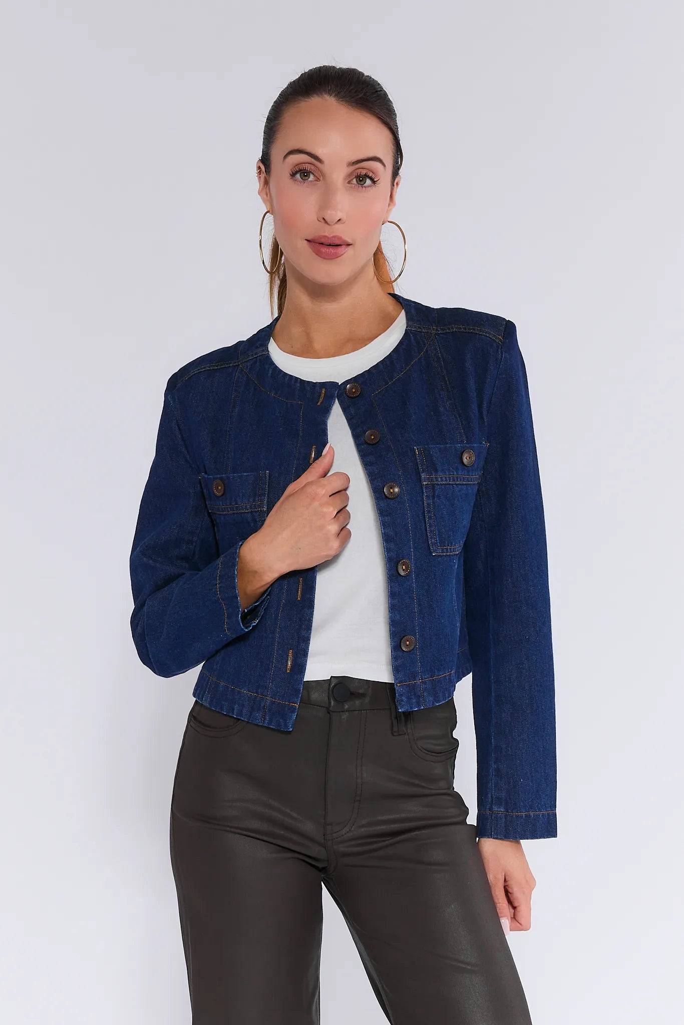 Woman wearing a blue denim Vera Jacket over a white shirt and black pants on a white background