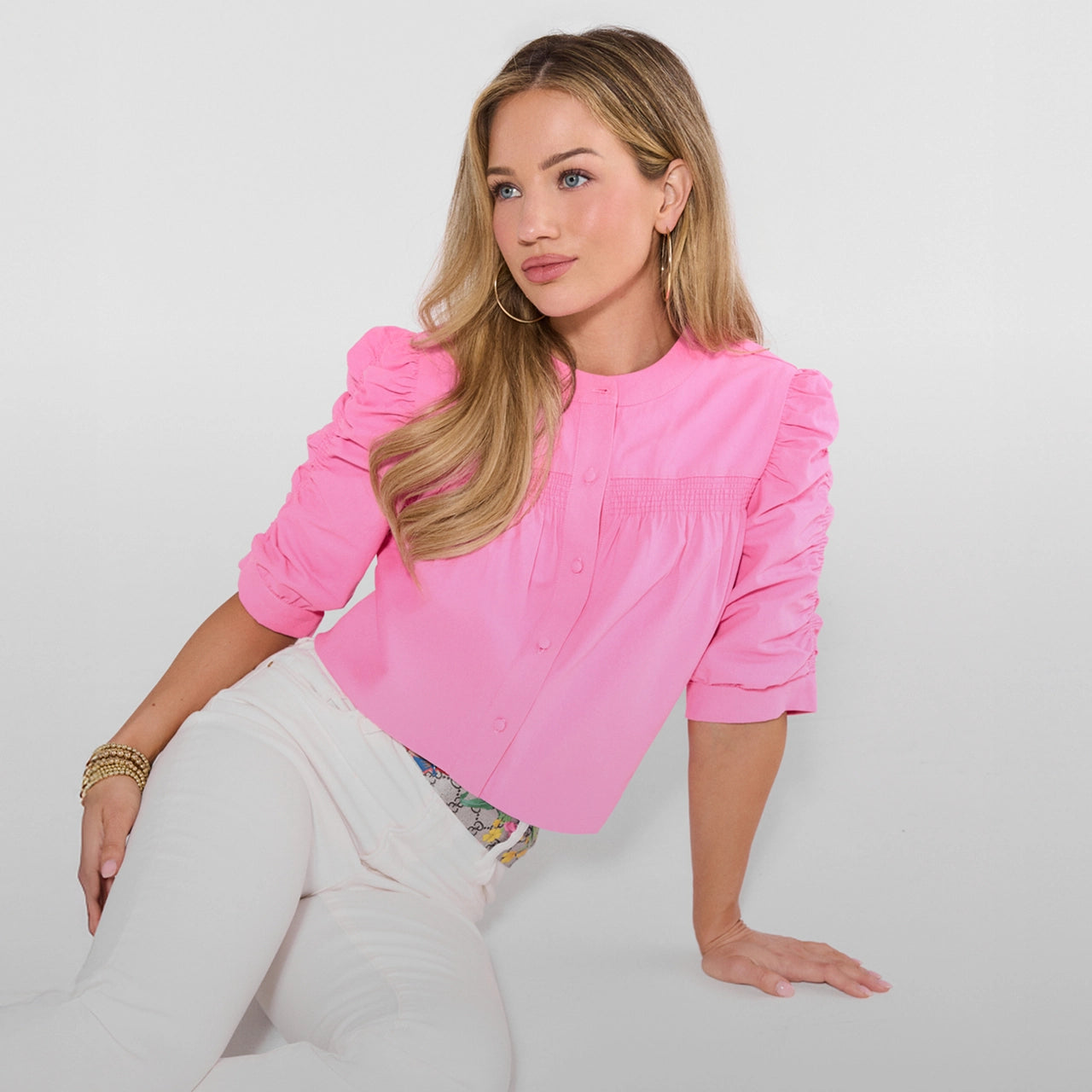 Woman wearing a pink blouse sitting on a white background