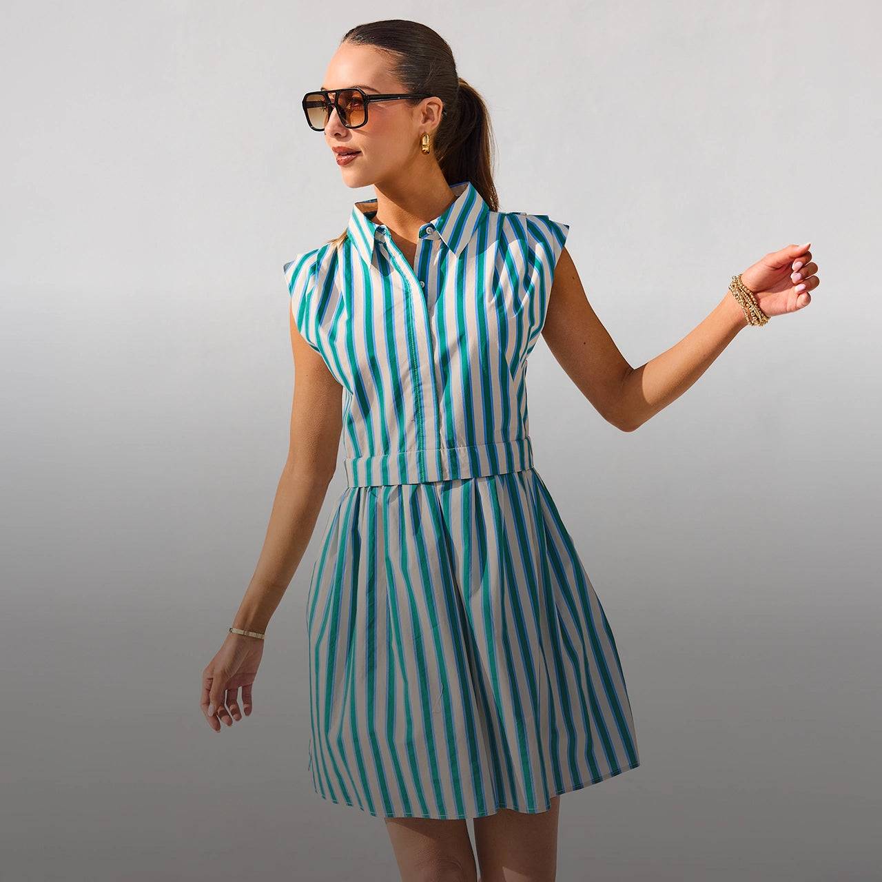Woman wearing a green and white striped dress against a gray background