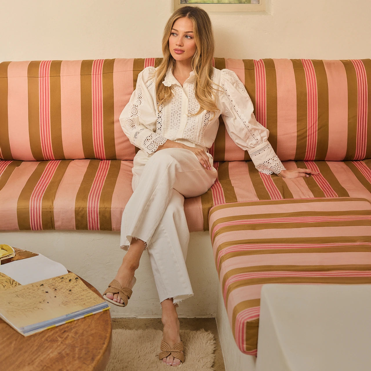 Woman sitting on a striped couch in a living room setting