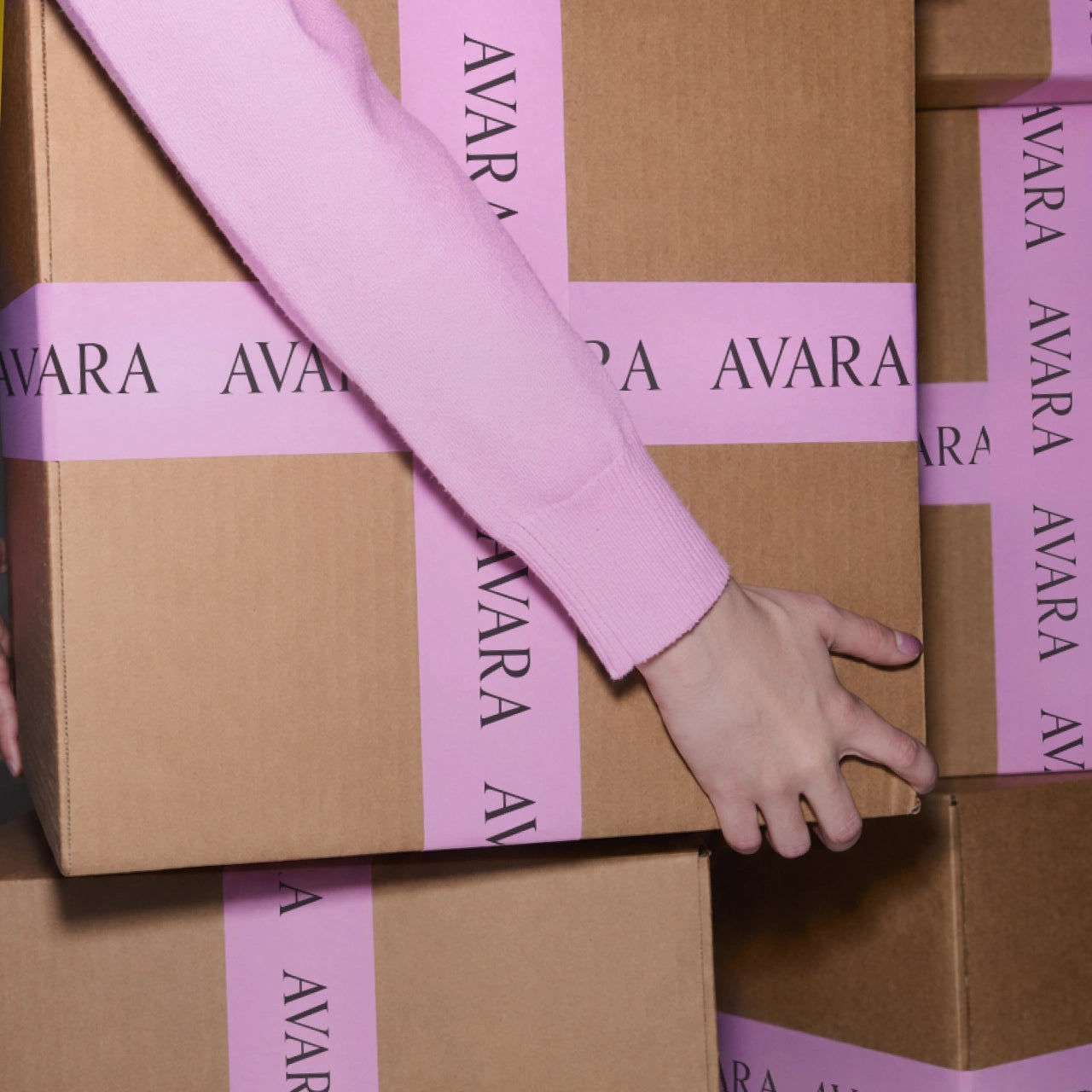 Person handling a box with 'Avara' branding on pink tape hero