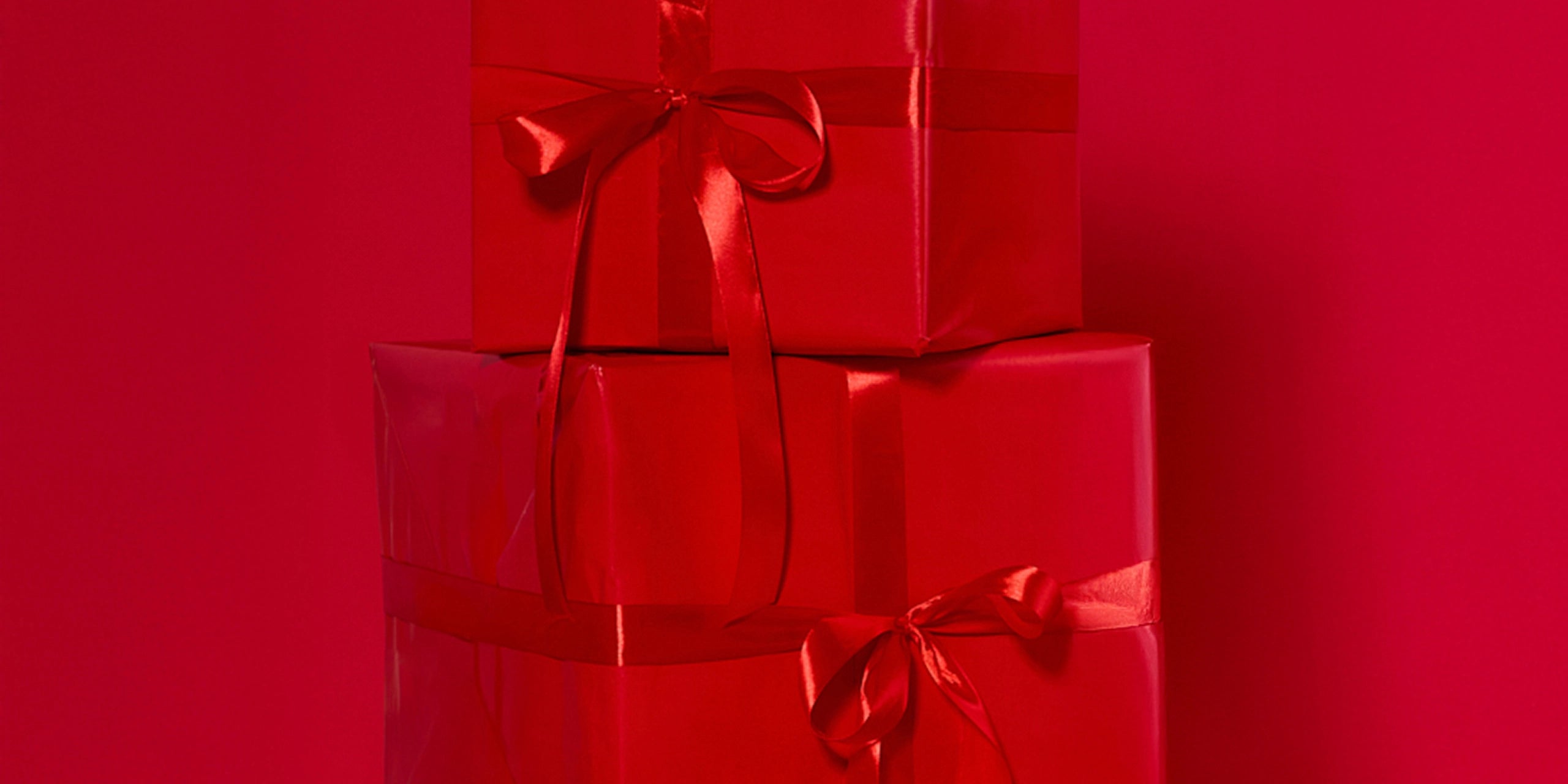 Two red gift boxes with ribbons on a red background
