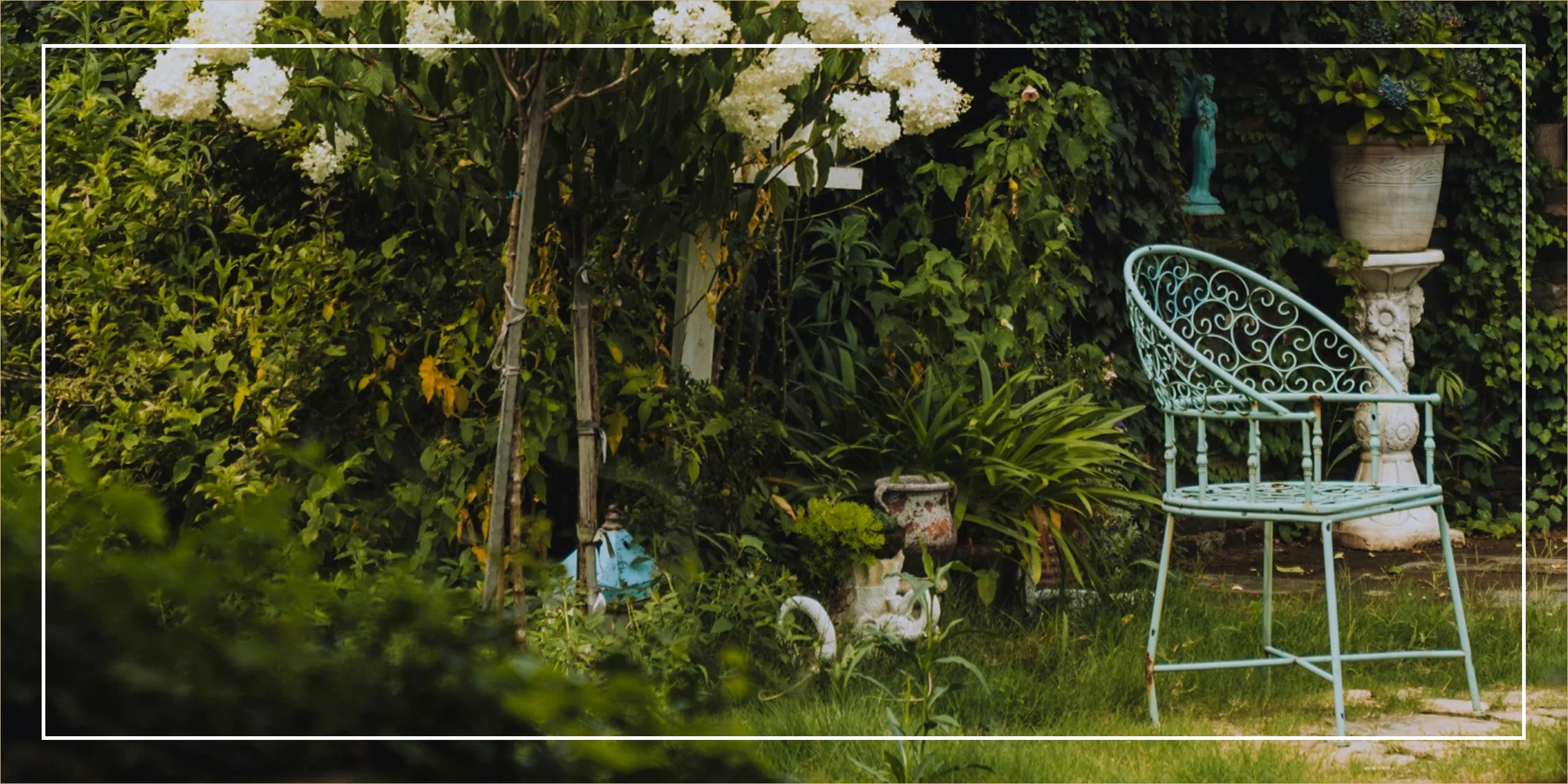 Decorative garden chair in a lush green garden with white flowers.
