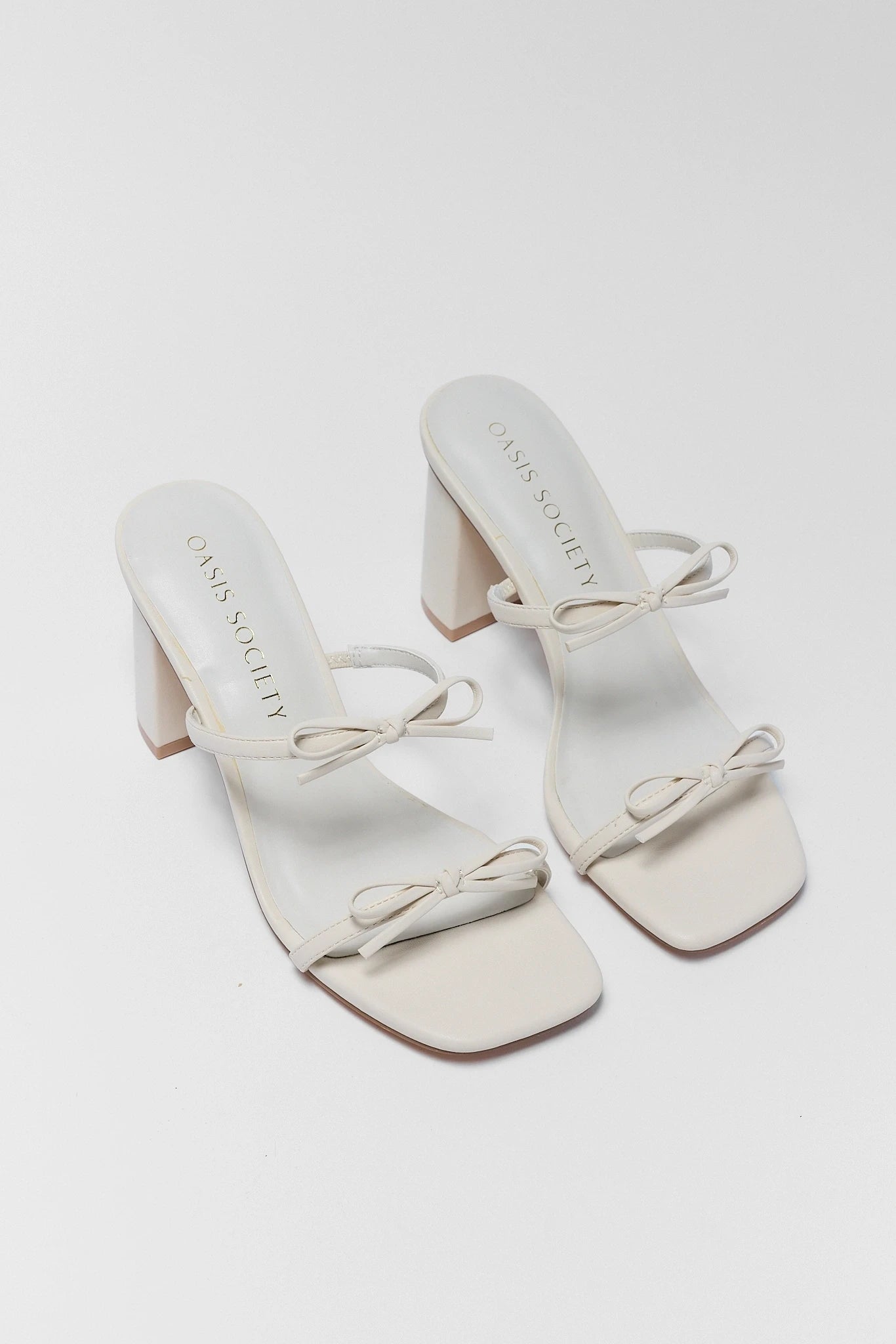 White sandals with bow details on a white background