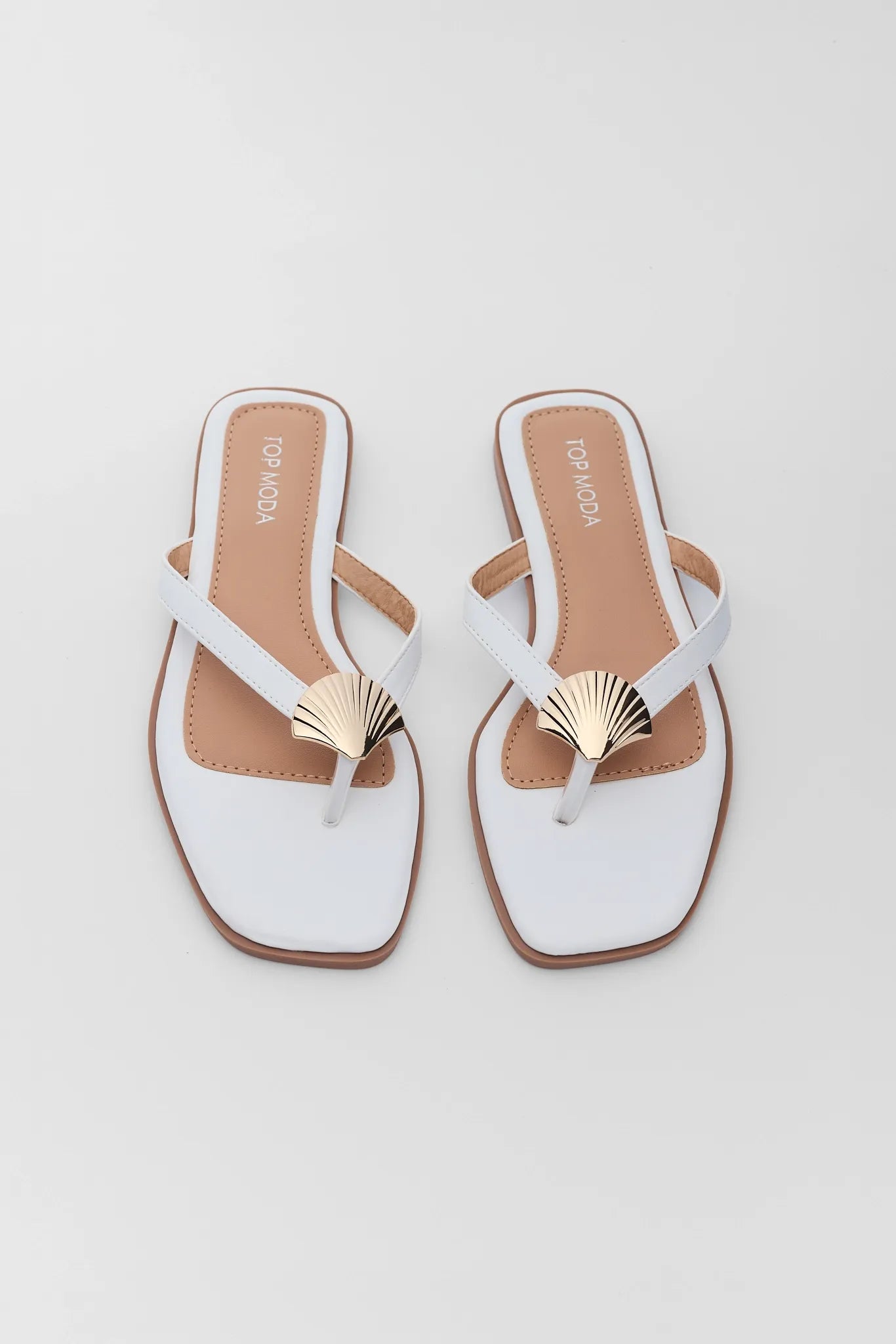 White sandals with gold accents on a light gray background two