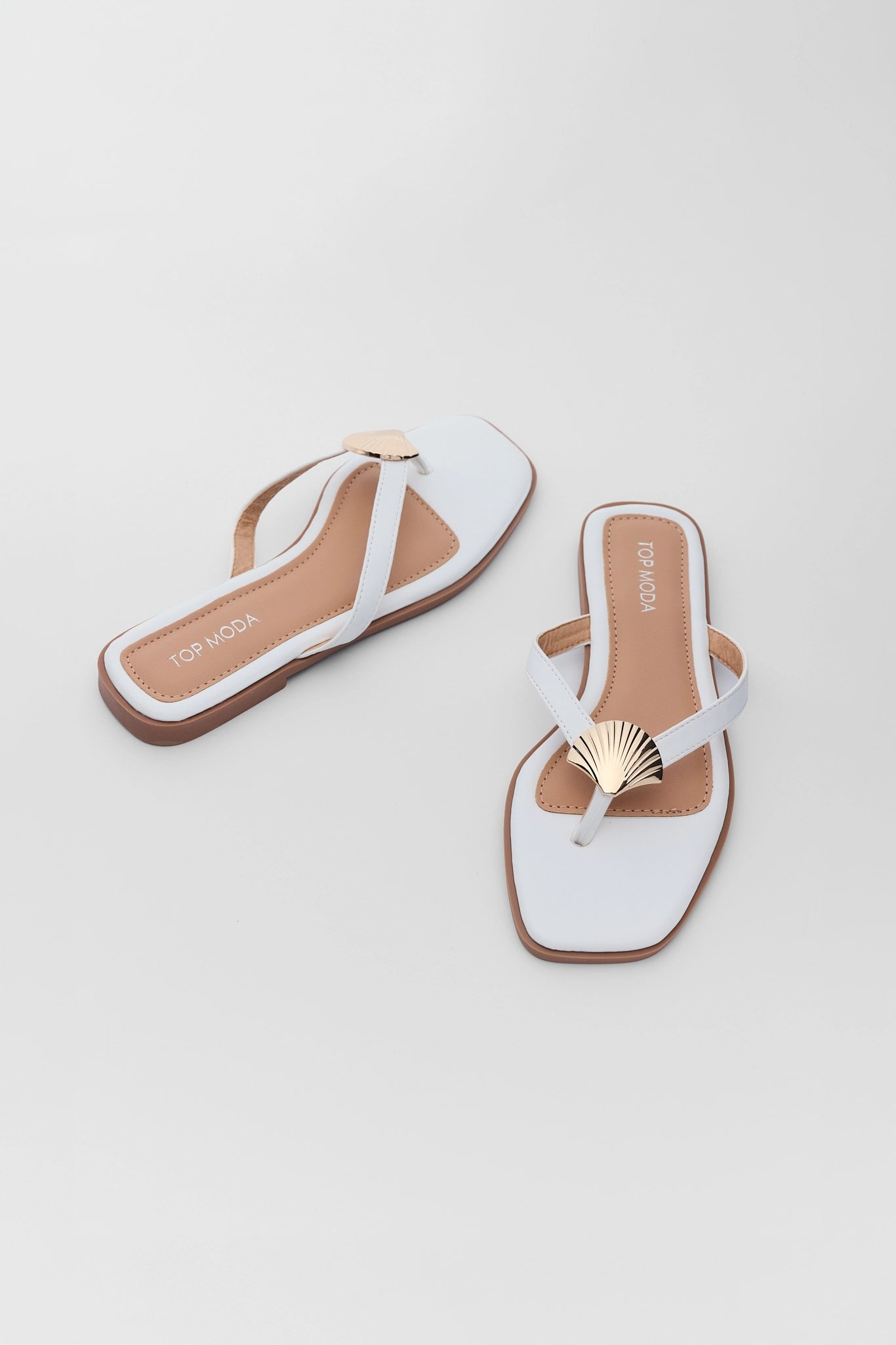 White sandals with gold accents on a light gray background