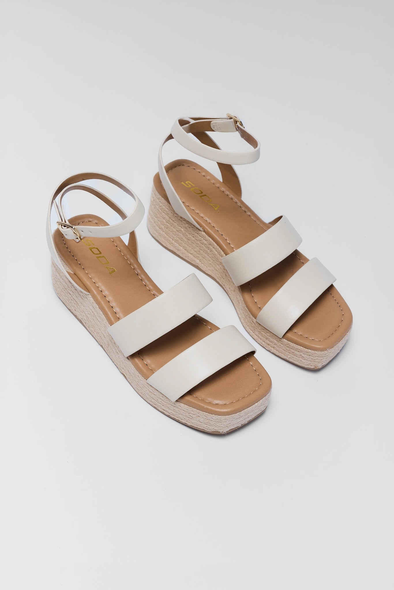 Pair of two white sandals with brown soles on a light gray background