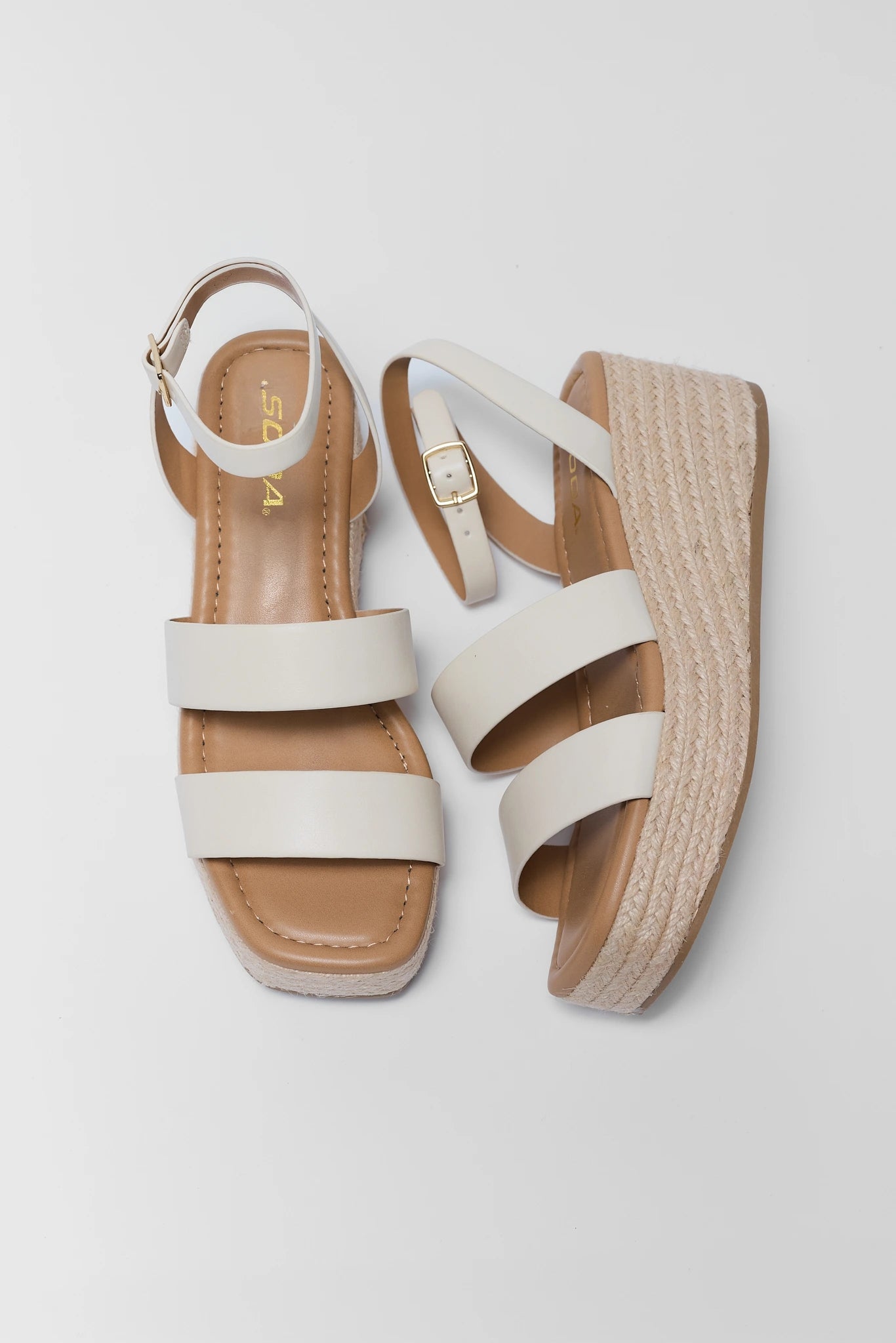 White sandals with brown soles on a light gray background