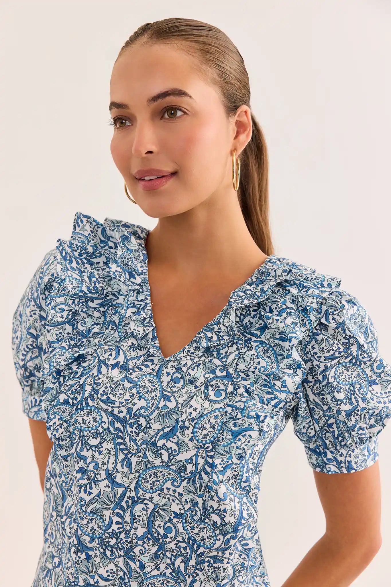 close up Woman wearing a blue floral dress against a plain background