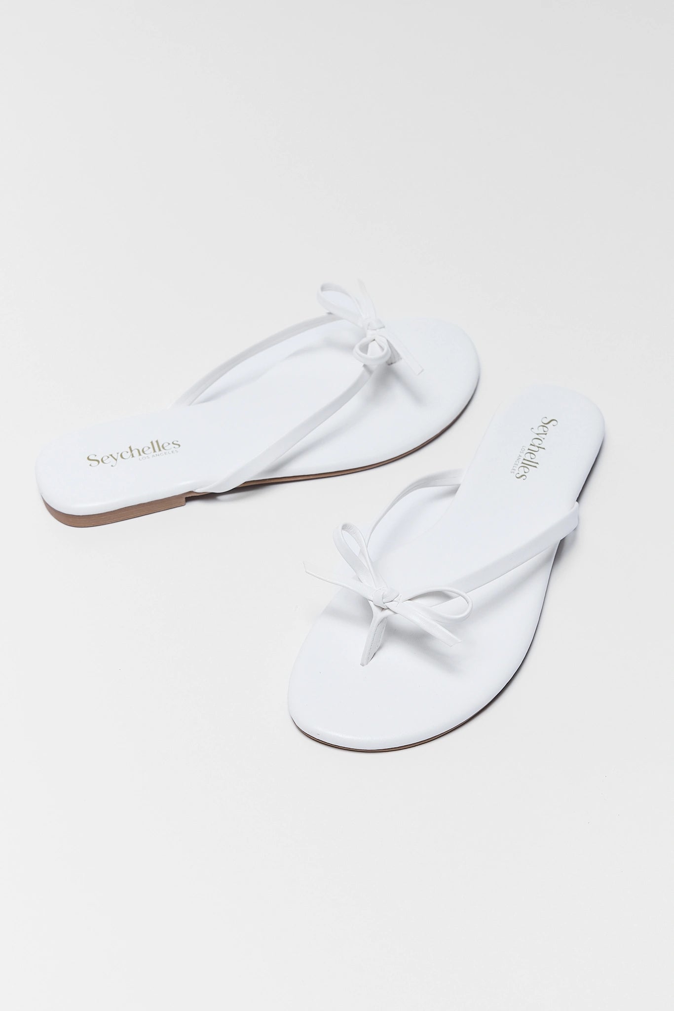 White flip-flops with branding on a white background