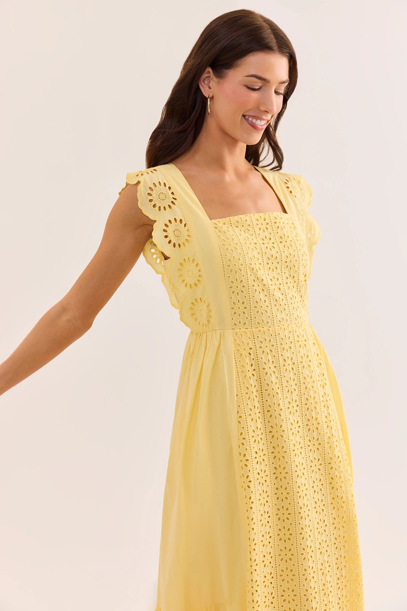 close up Woman wearing a yellow crochet dress against a plain background