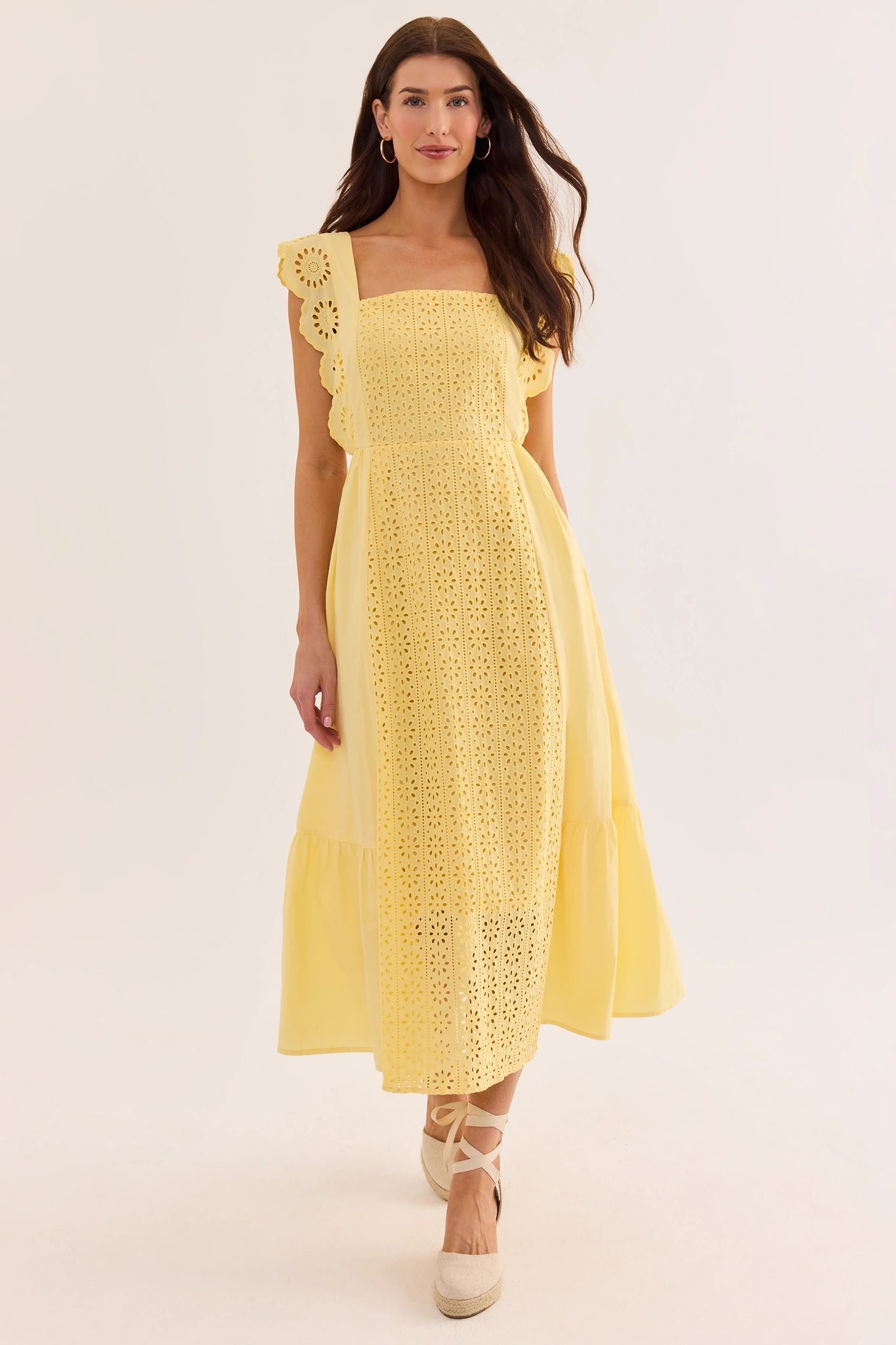 Woman wearing a yellow dress with floral details on a beige background lifestyle