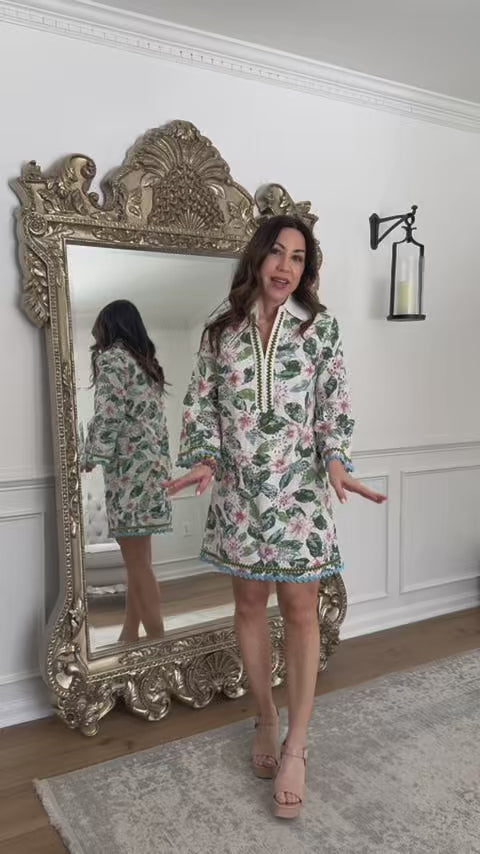woman wearing a floral long sleeve short dress with a mirror in the background
